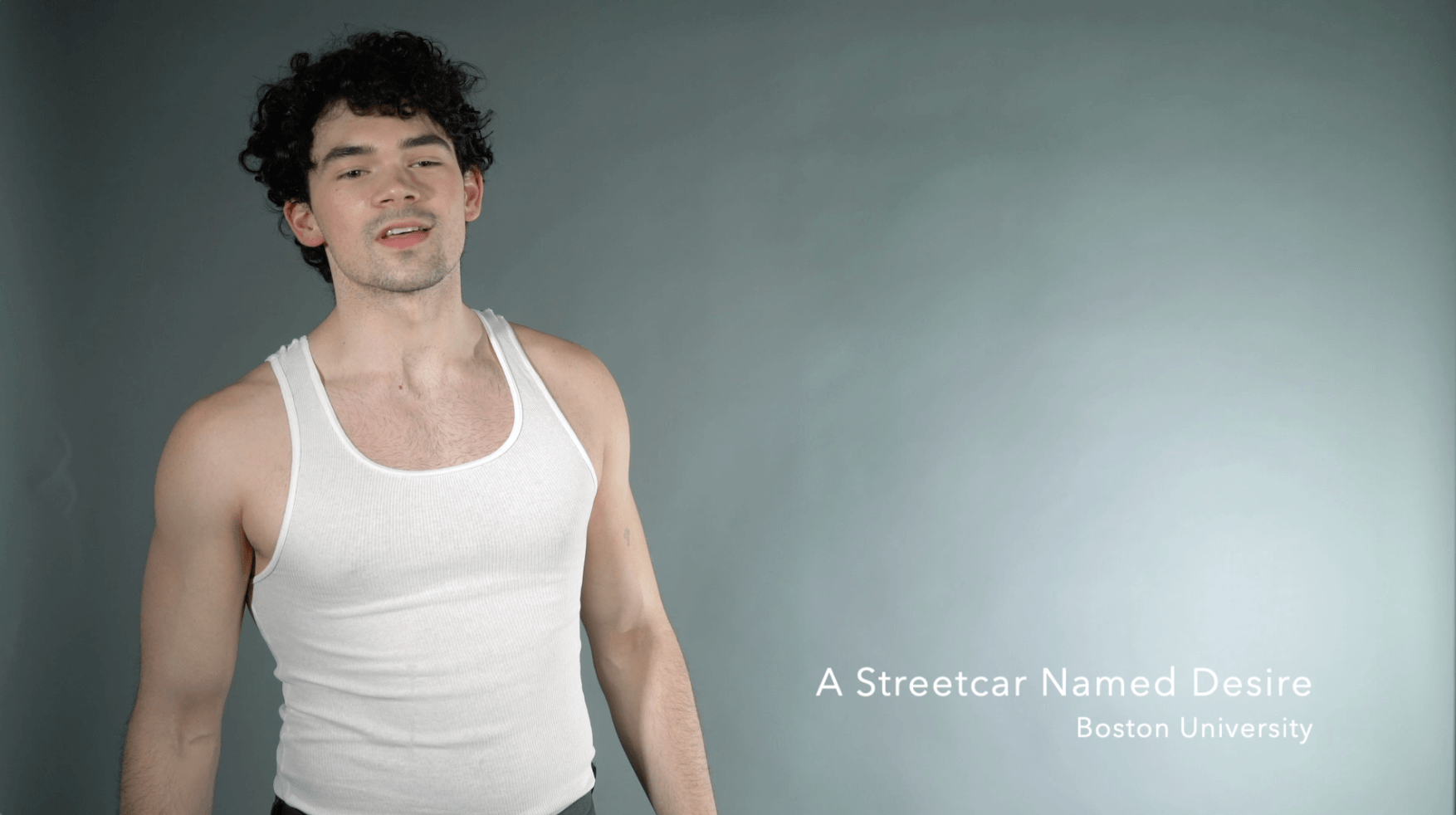 A young man with curly dark hair wearing a white tank top, standing against a plain gray background, with text overlay reading "A Streetcar Named Desire" and "Boston University."