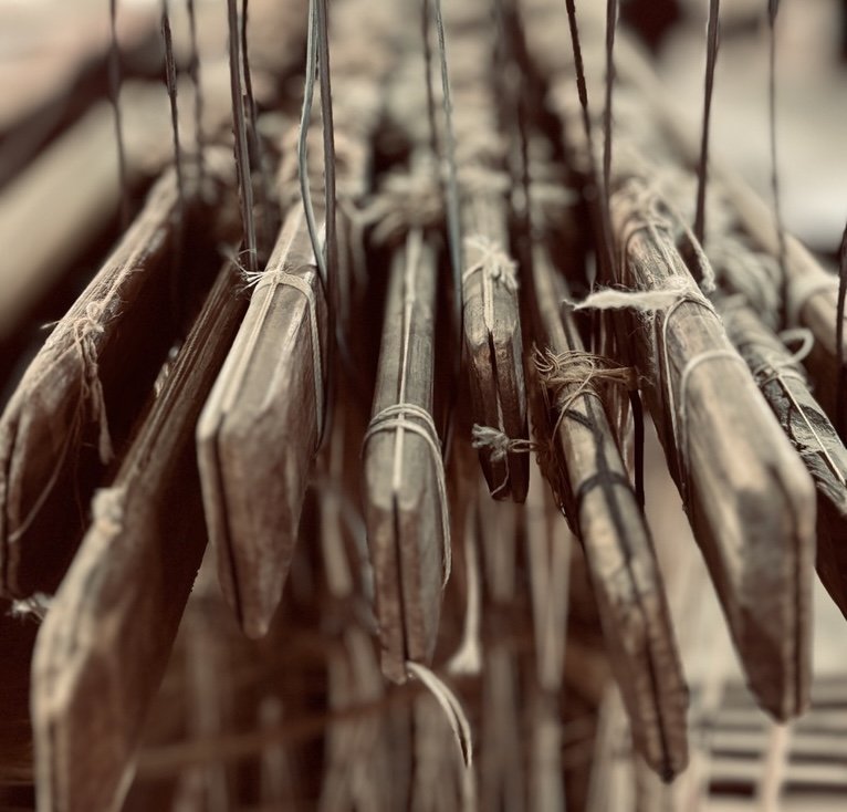 A close-up of antique wooden and metal hinges or fasteners hanging on strings in a rustic setting.