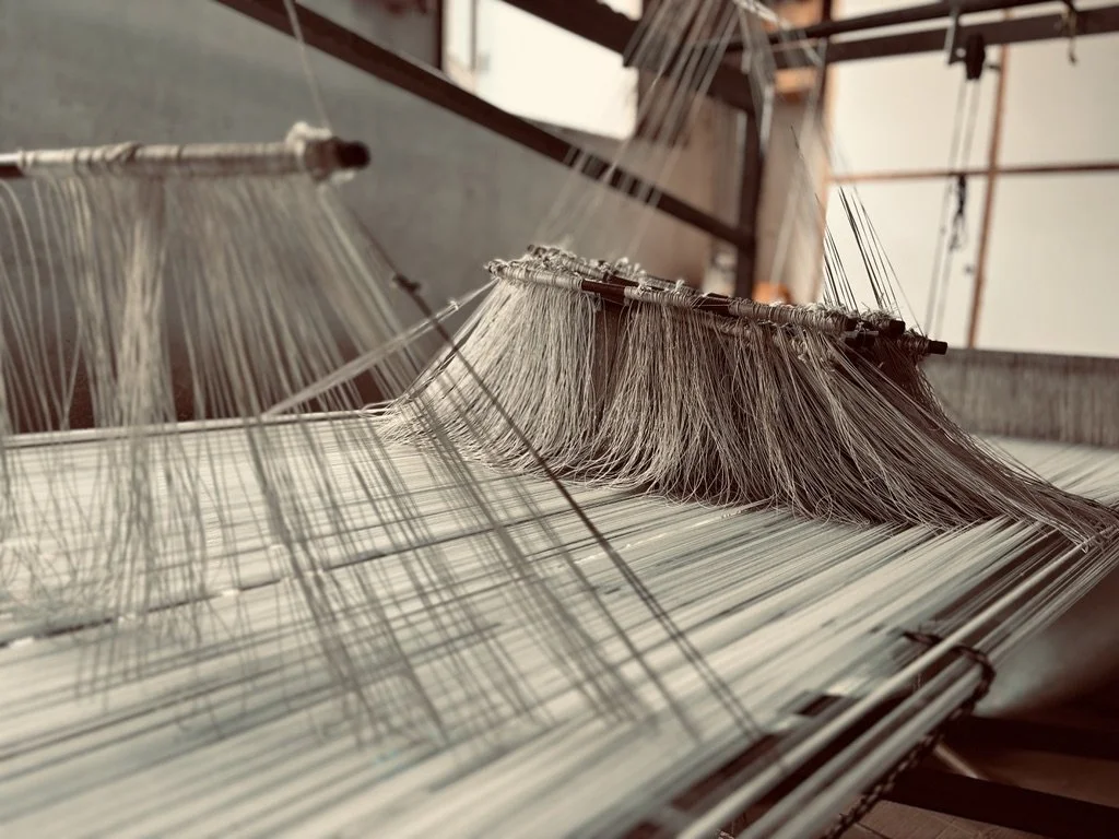 Close-up view of a traditional loom with threads and weaving tools in a textile workshop.