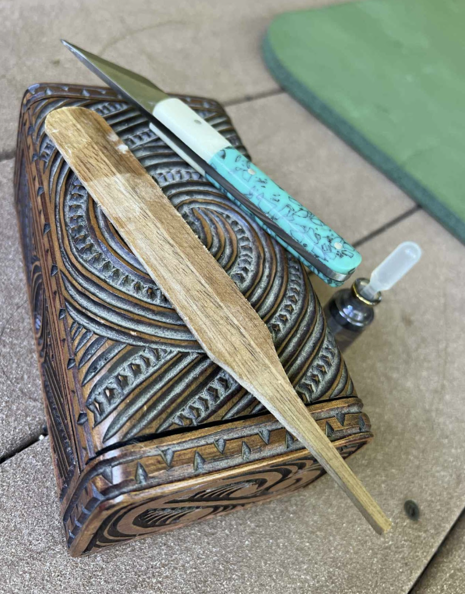 Ceremonial tools used to prepare Kambo medicine, including carved wooden box, application stick, knife, and dropper bottle.”