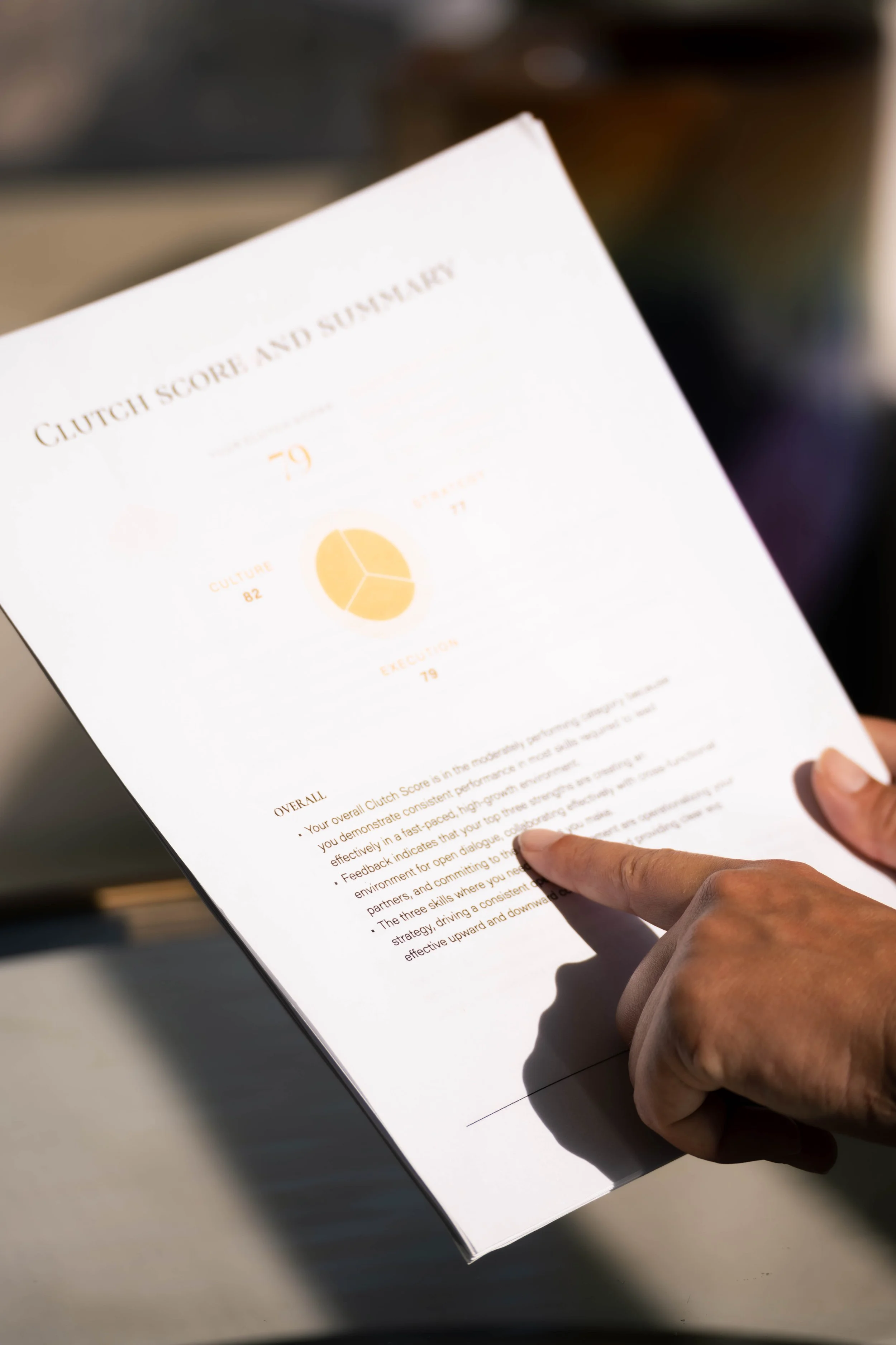 A person holding a printed report titled "Clutch Score and Summary" with a pie chart and some text on the page.