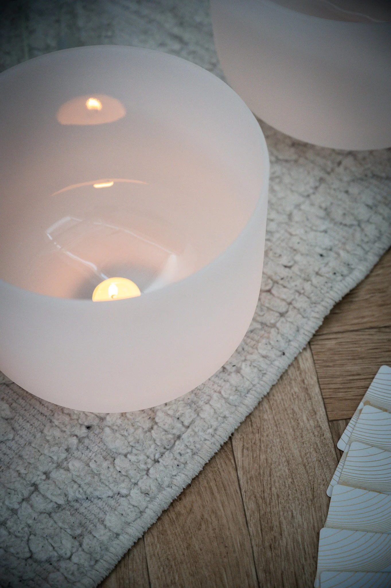 Two brass singing bowls, a mallet, and a small percussion hammer on a wooden floor.