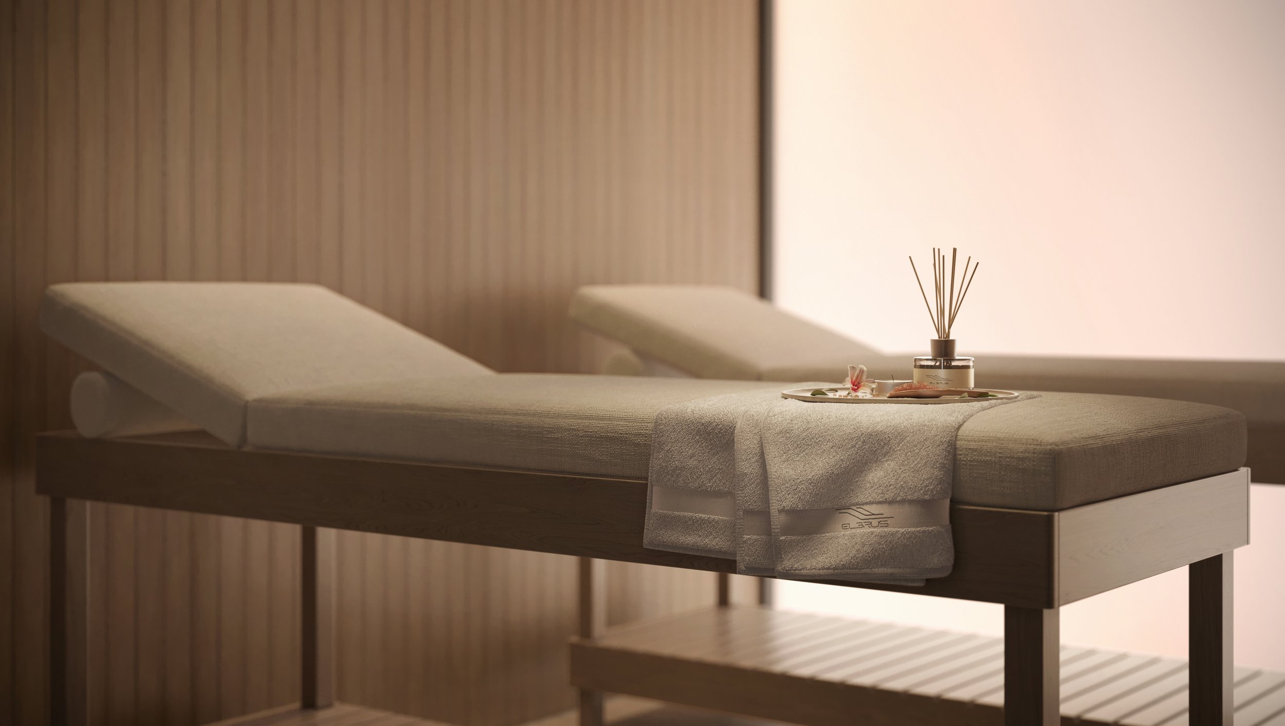 Mesma cama sendo preparada para uma sessão de massagem, com toalha branca e itens de aromaterapia ao lado.