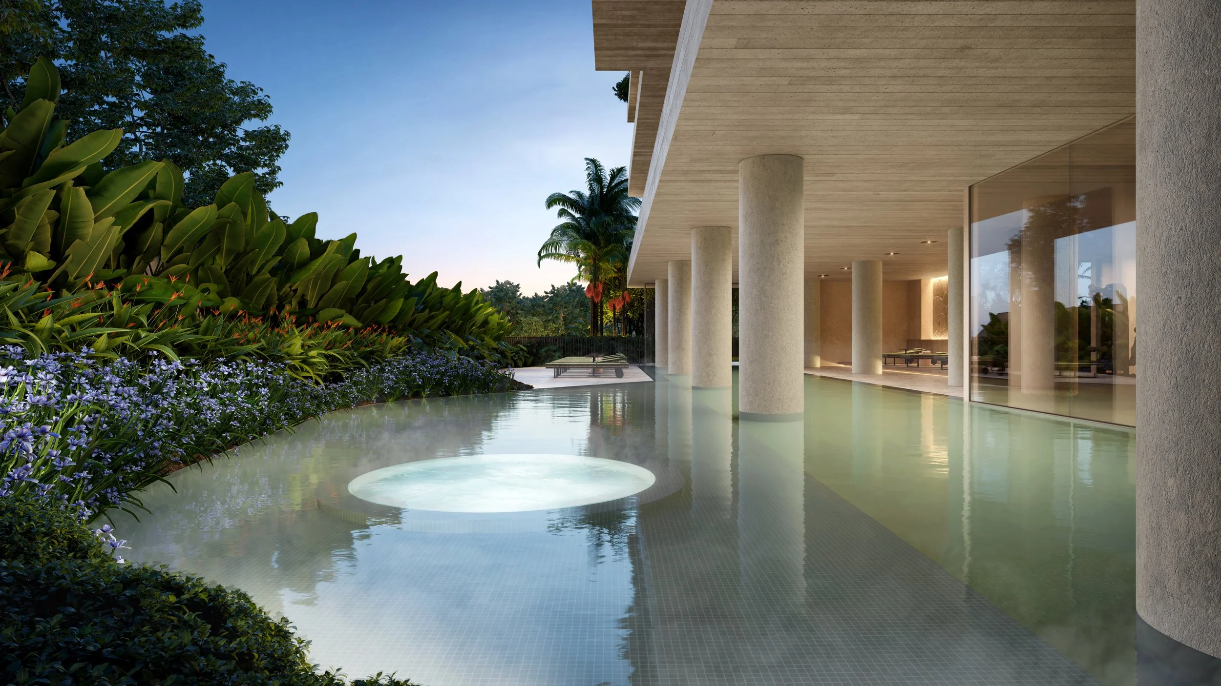 Piscina com borda infinita ao lado de uma área de descanso coberta, rodeada de plantas e flores, com vista para o céu ao entardecer.