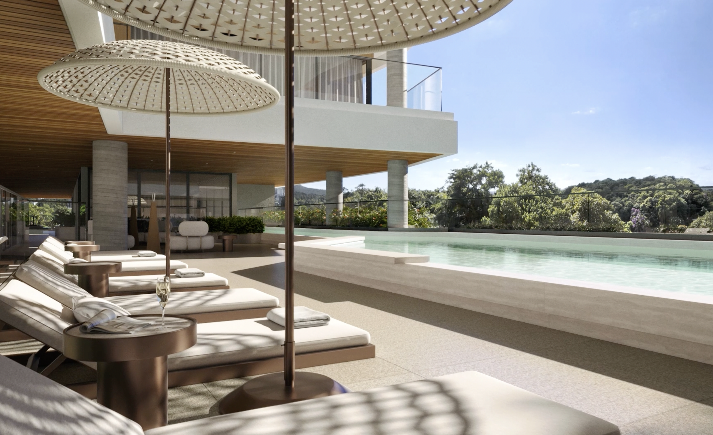 Área de piscina com espreguiçadeiras brancas, guarda-sol de palha, piscina de borda infinita, estrutura moderna, cercada por árvores e céu claro.