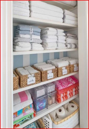 Shelves filled with folded towels, linens, and toiletries in organized baskets and containers.