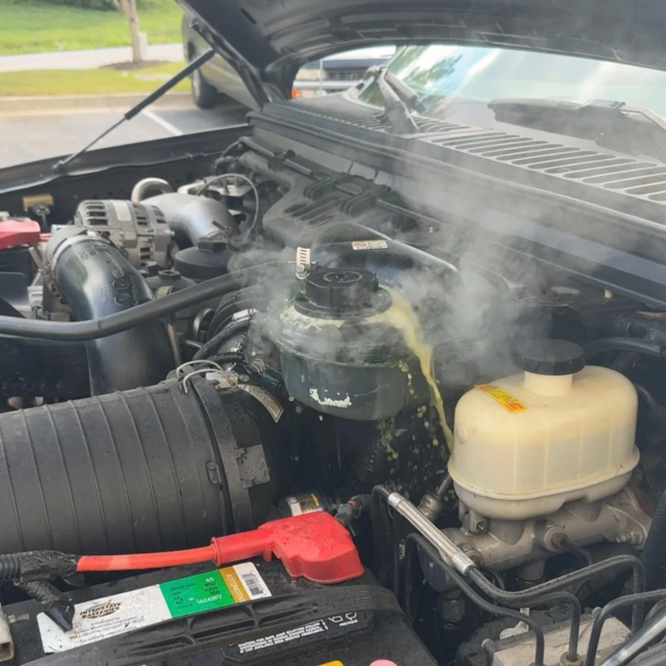 Ford Powerstroke engine bay showing a coolant leak with visible steam