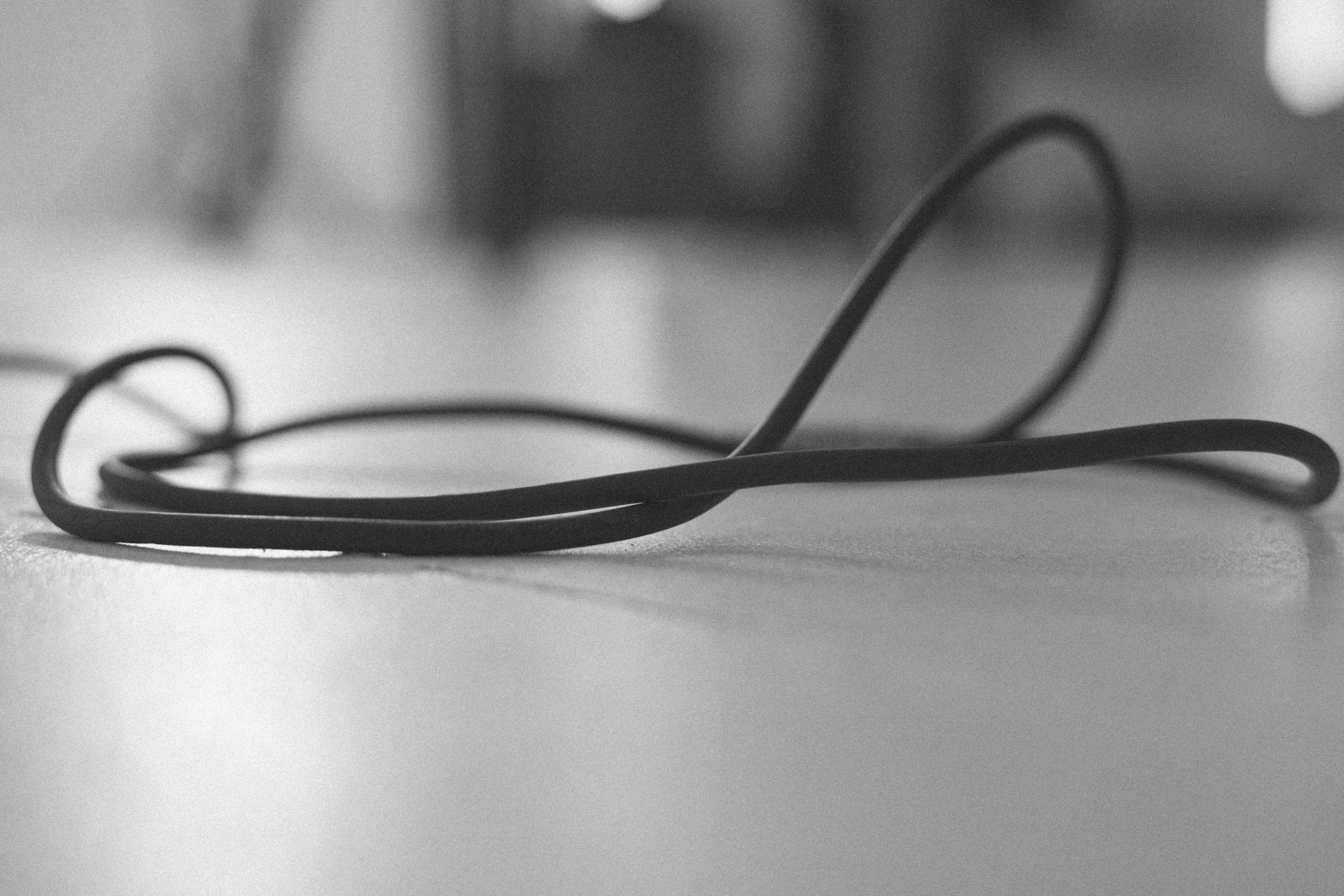 A black rubber band lying on a smooth surface with a blurred background.