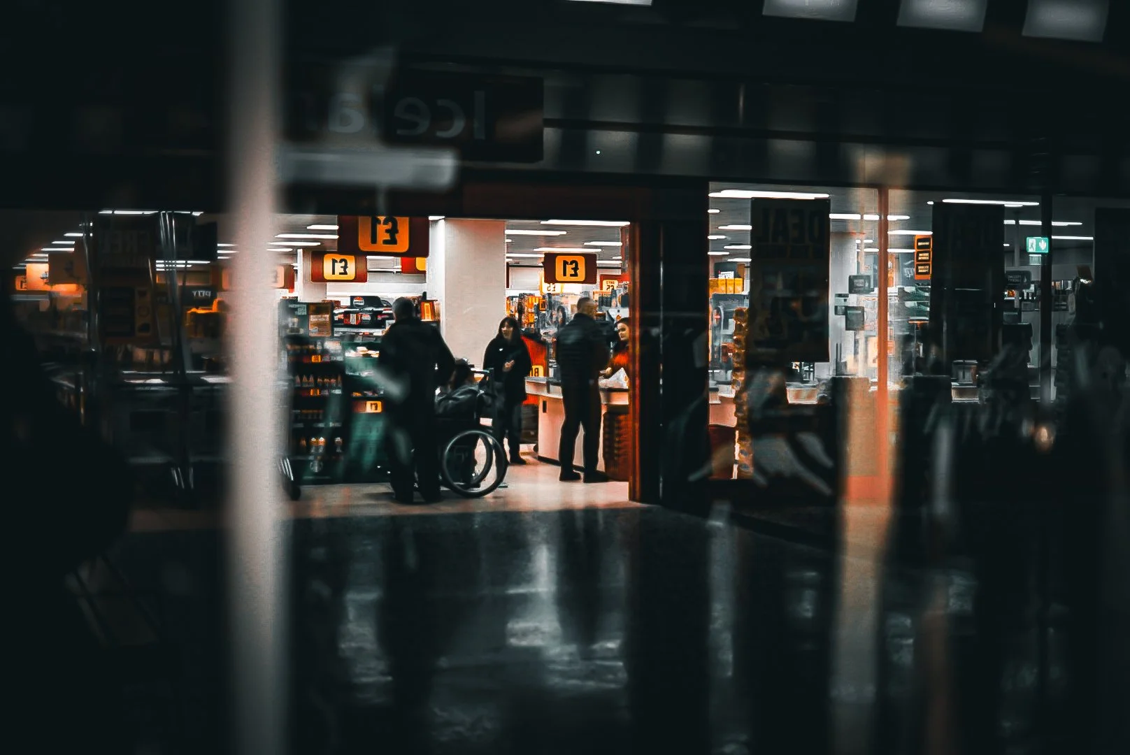 View of people inside an airport terminal near the check-in counters, with luggage and airport signage visible.