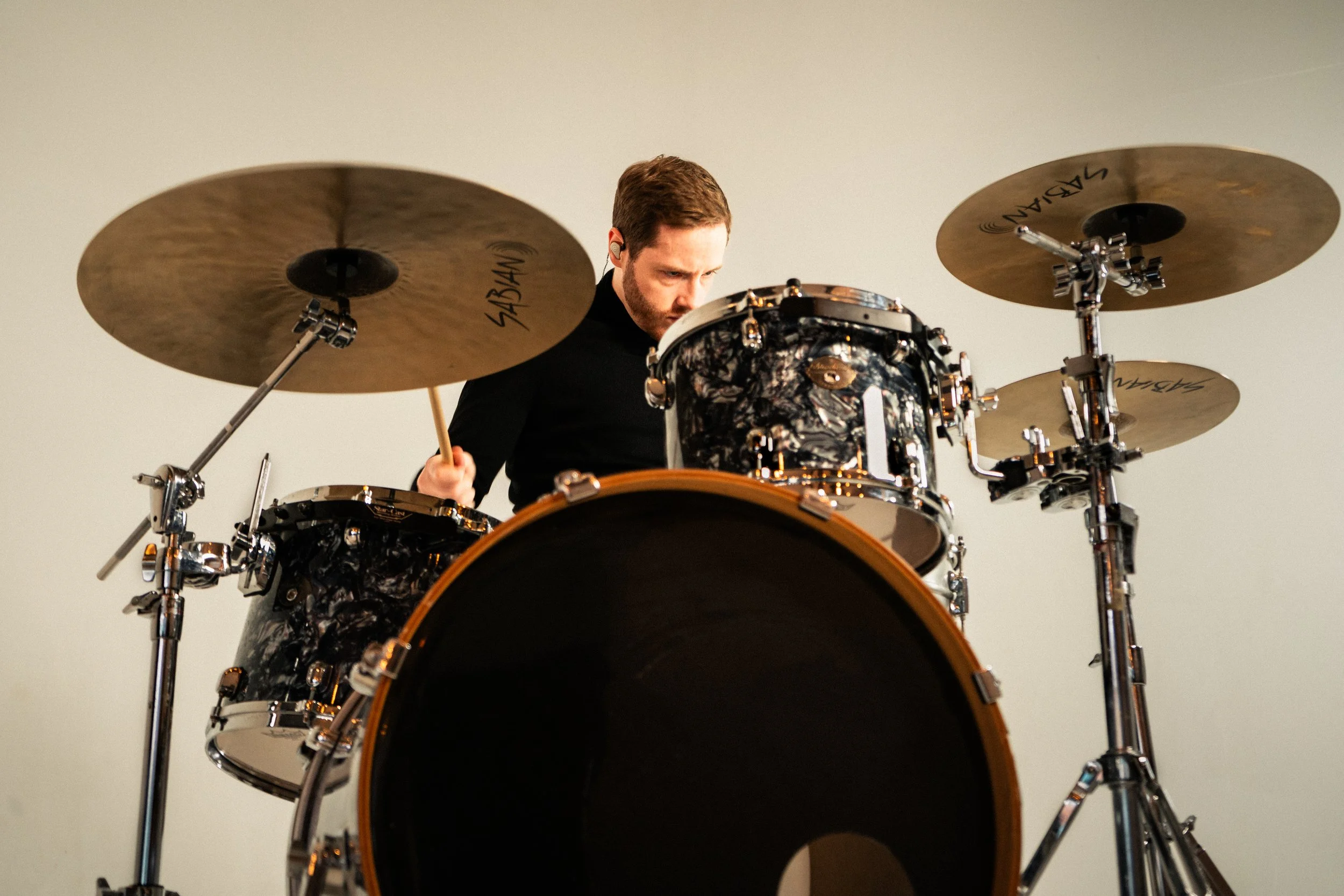 A man playing an electronic drum set with drums and cymbals, focused on his performance.