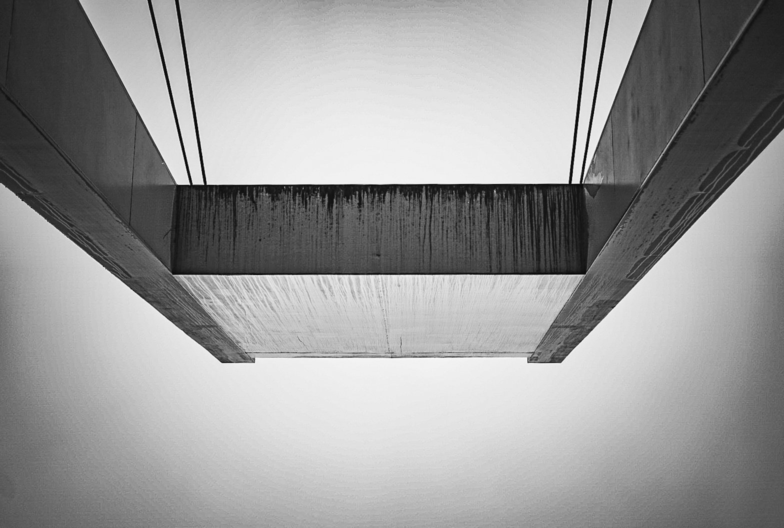 Black-and-white photograph looking up at a modern architectural building with sharp angles, straight lines, and textured surfaces.