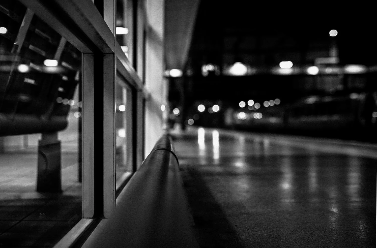 Empty outdoor bus stop at night with benches and blurred city lights in the background.