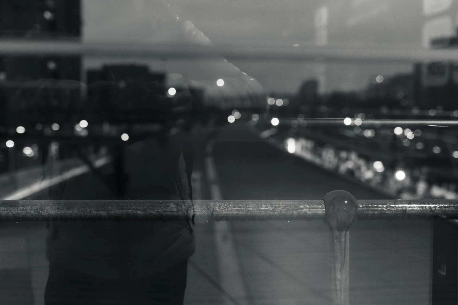 Reflection of a person taking a photo in a glass display case with cars in the background.