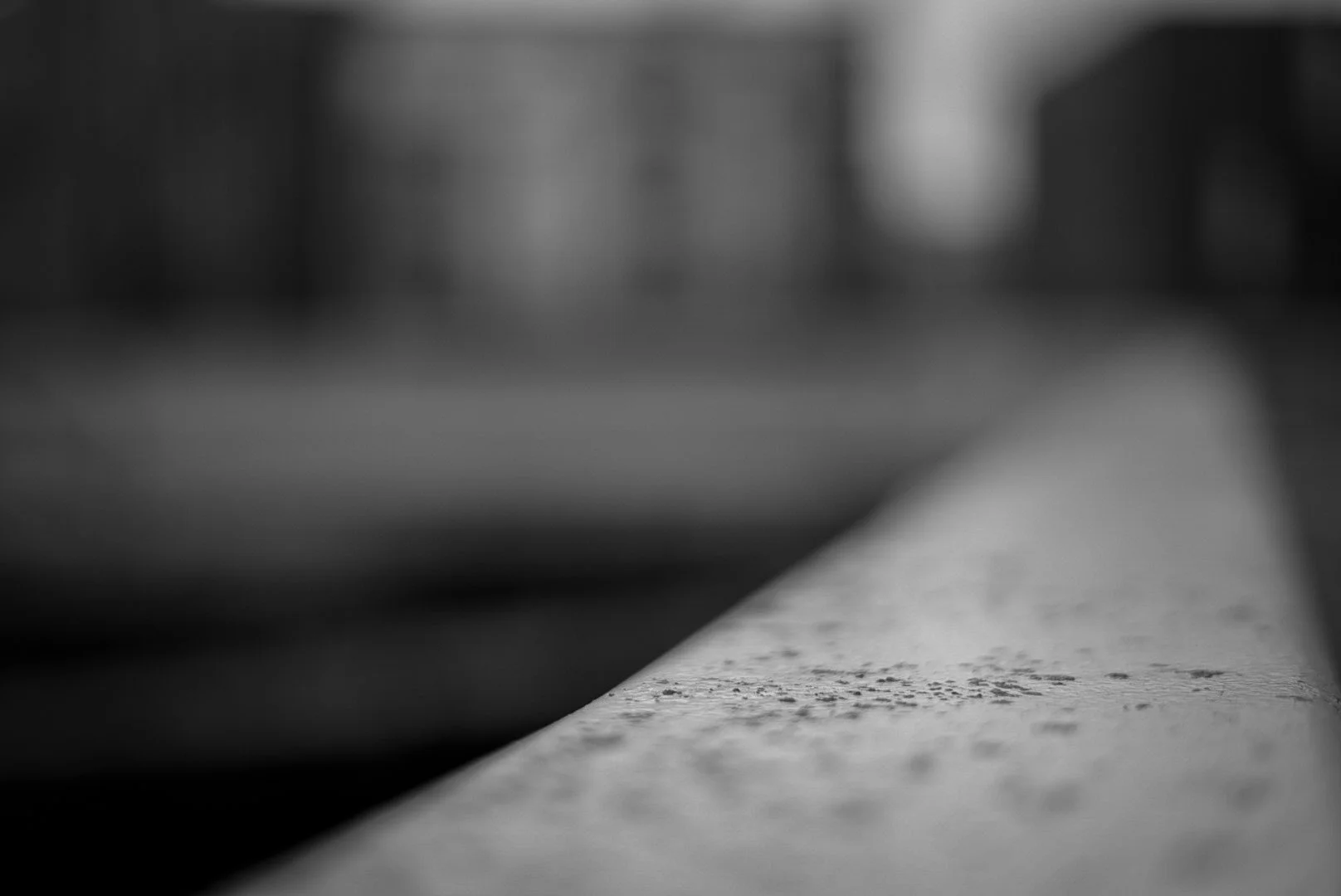 Close-up of a textured, slightly worn concrete or stone surface with a blurred background, in black and white.