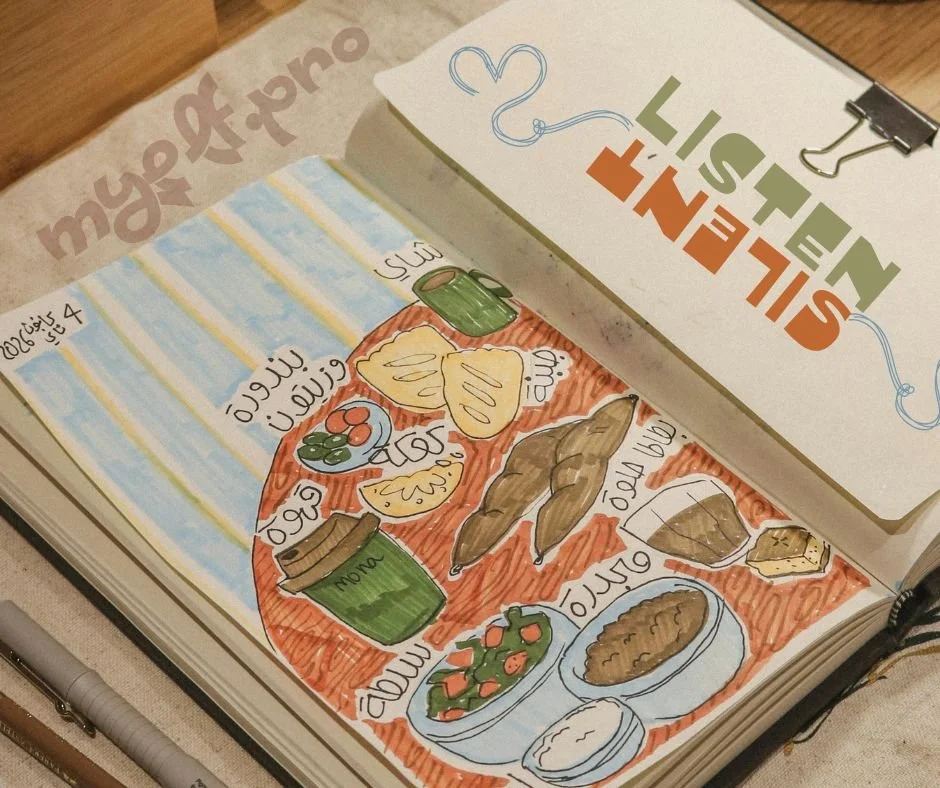 Un album illustré montrant une table avec des plats traditionnels, incluant des légumes, un pain, une bouteille de sauce, et une feuille de menthe, avec un fond coloré en orange