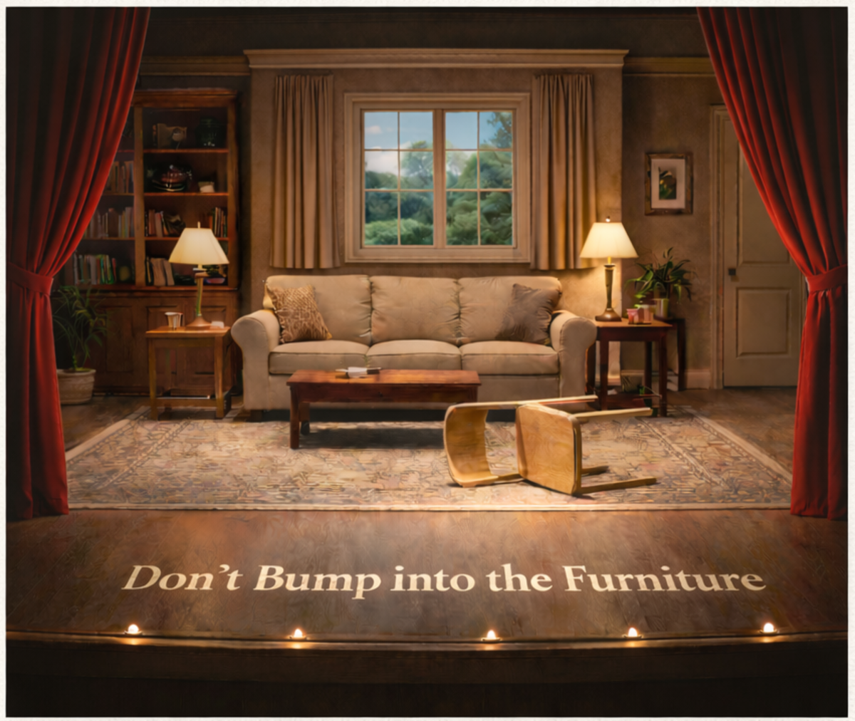 A living room stage set framed by red theatre curtains. A wooden chair lies tipped over in the foreground on a stage floor that reads Don't Bump into the Furniture, illuminated by small footlights.