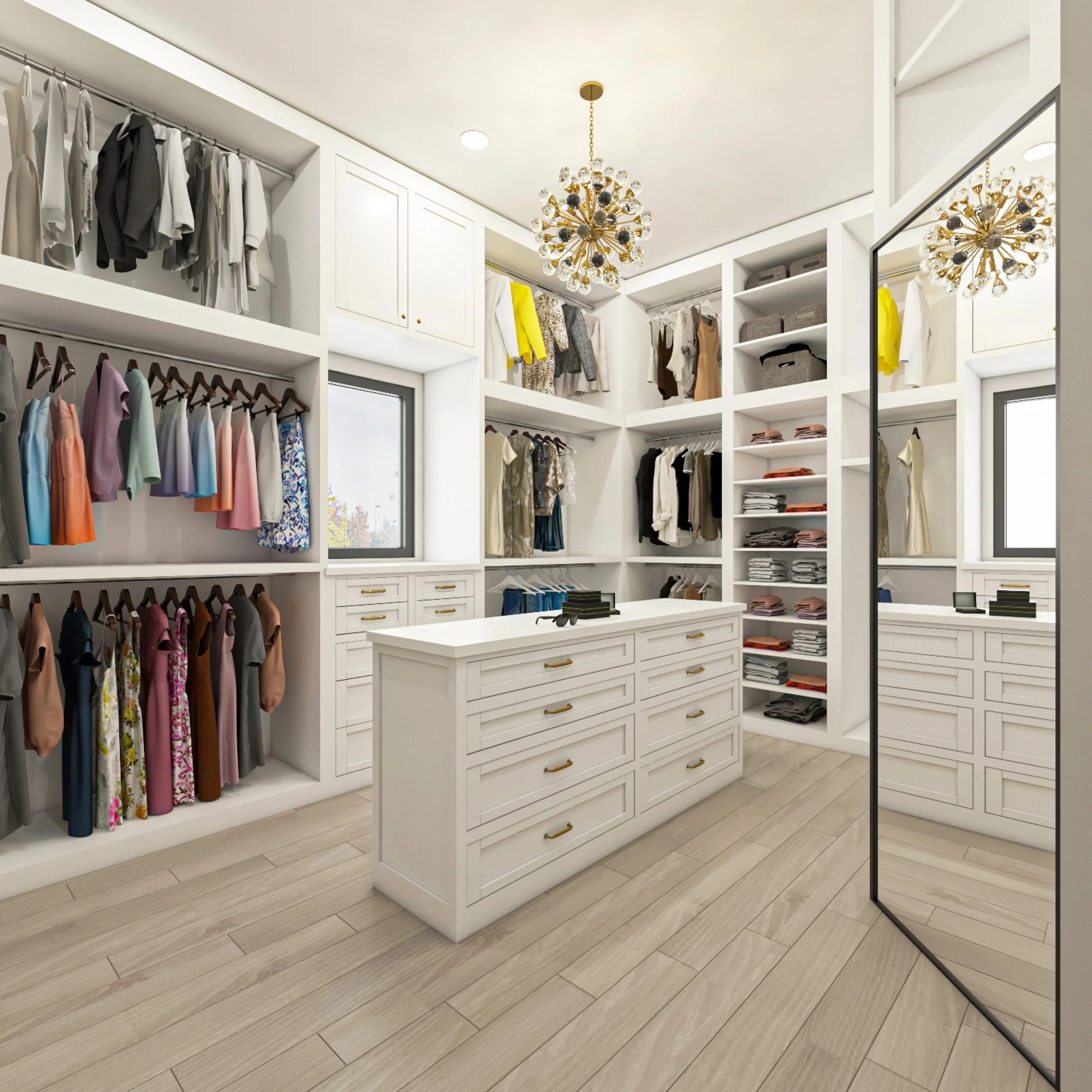 A walk-in closet with white built-in shelving units containing neatly folded clothes, hanging garments, and storage baskets. A white island dresser with gold handles is in the center, and a chandelier hangs from the ceiling. There is a sliding mirror door on the right and a window showing a view outside.