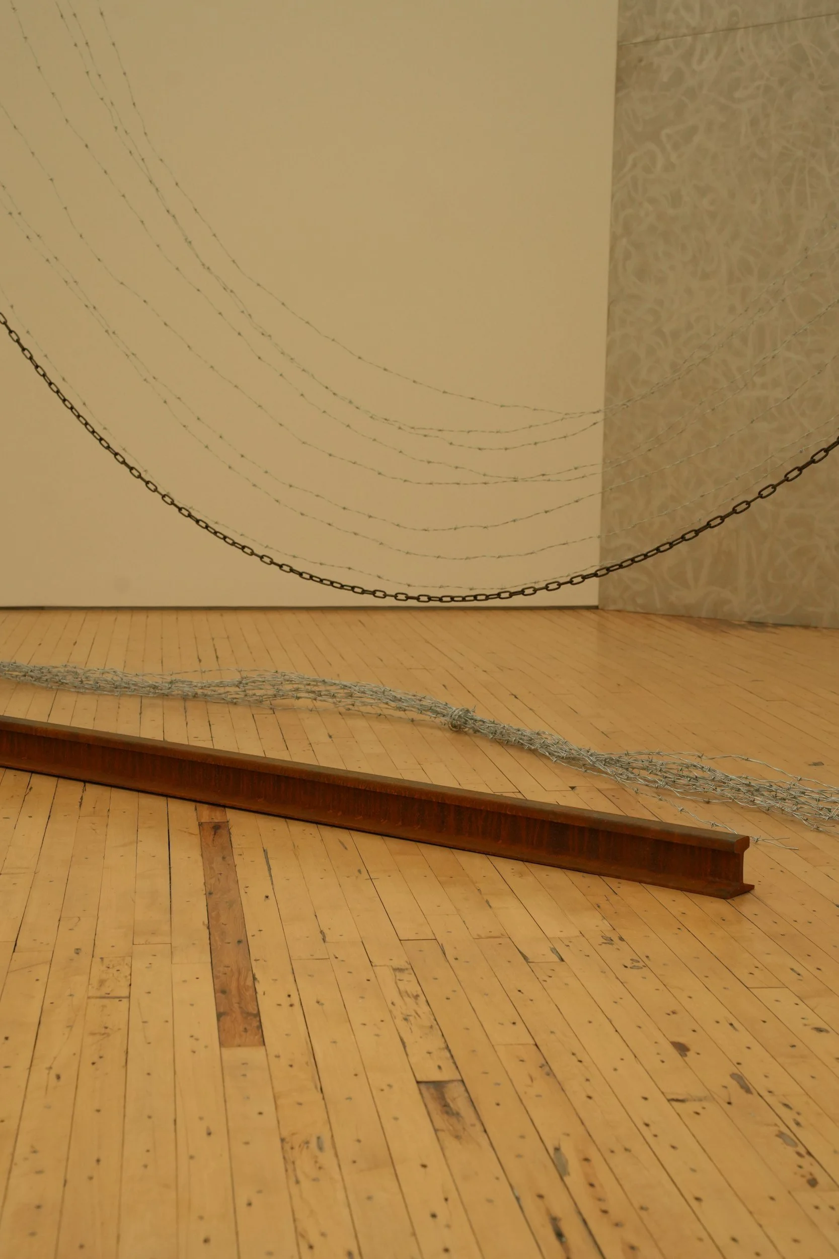 Art installation with chain link sculptures and abstract wire chains on the wooden floor of an art gallery.