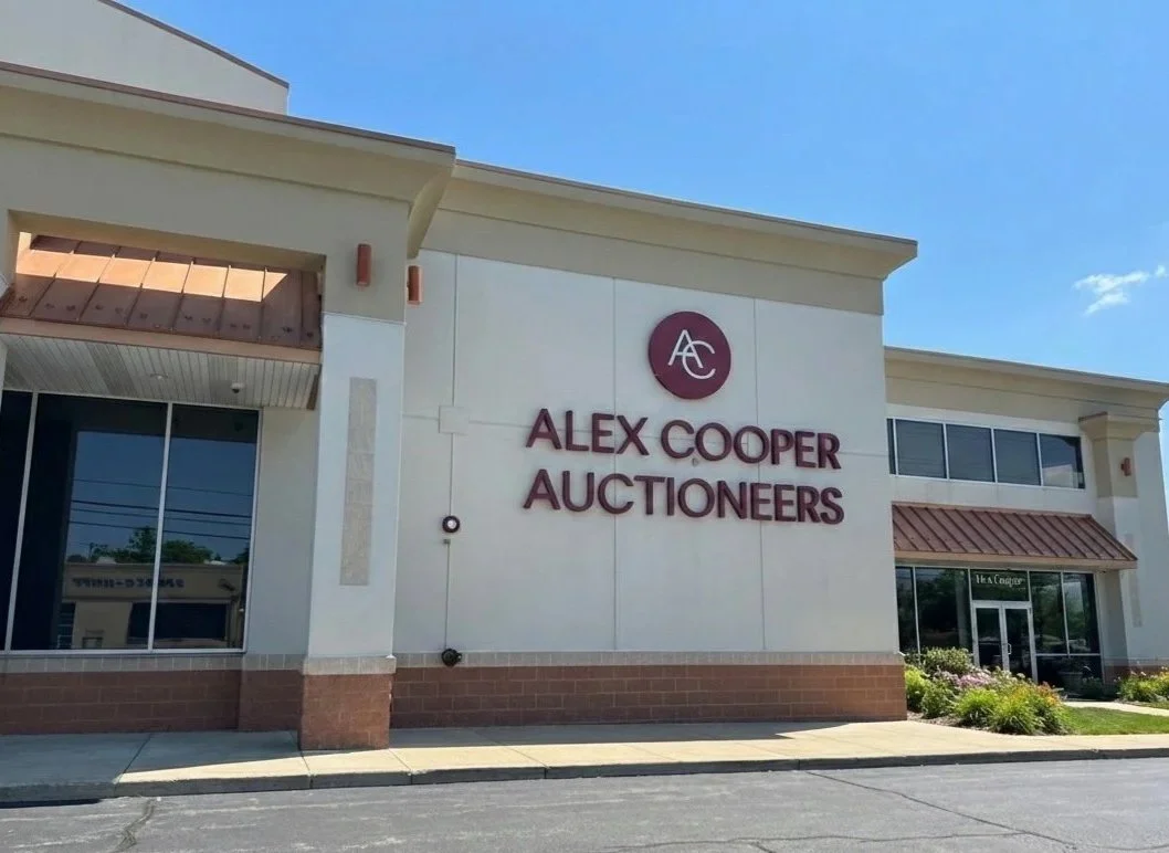 Exterior view of a building with a sign for Alex Cooper Auctioneers on the wall.
