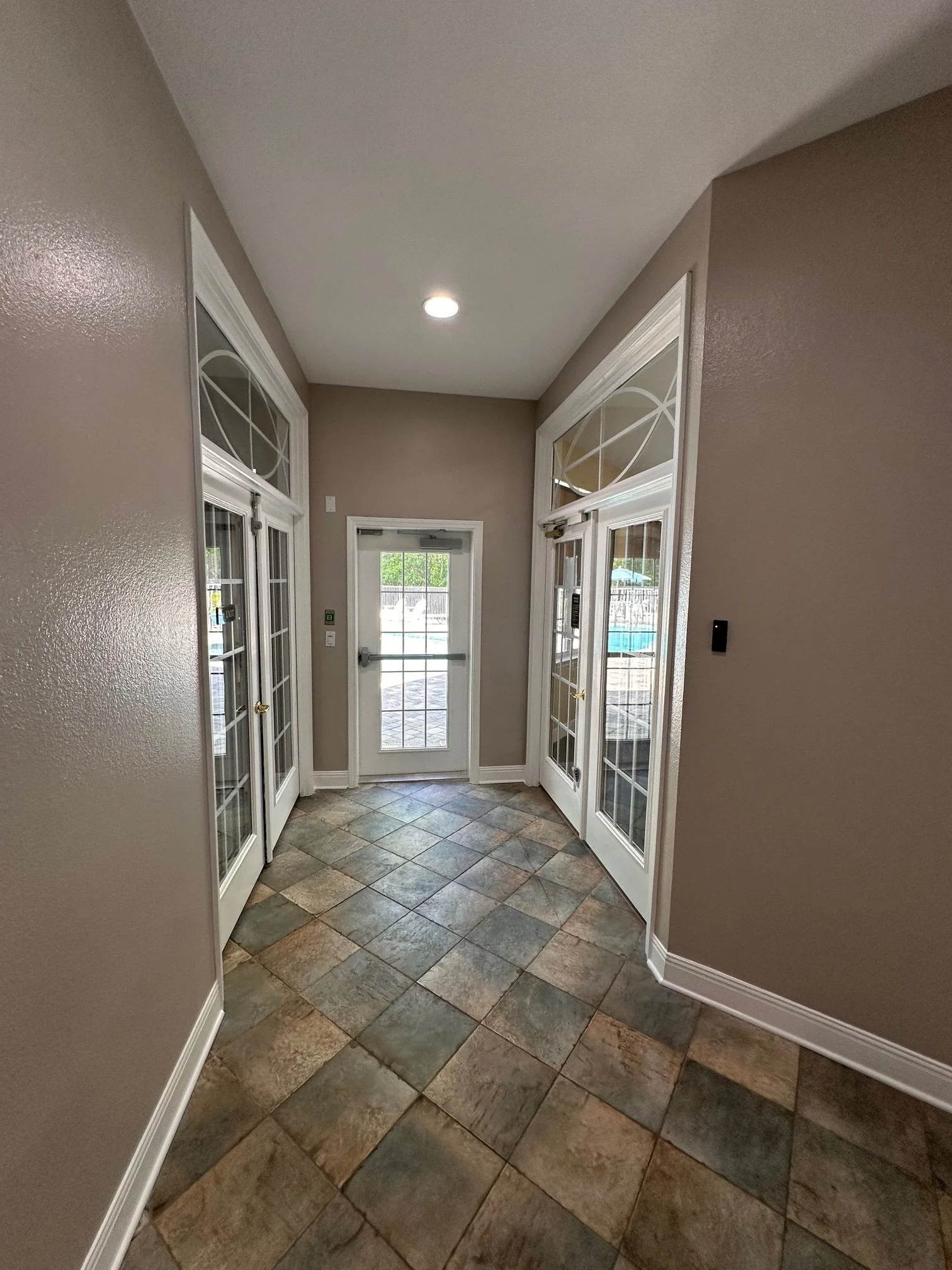 Entryway with a tiled floor, beige walls, glass double doors, and ceiling with recessed lighting.