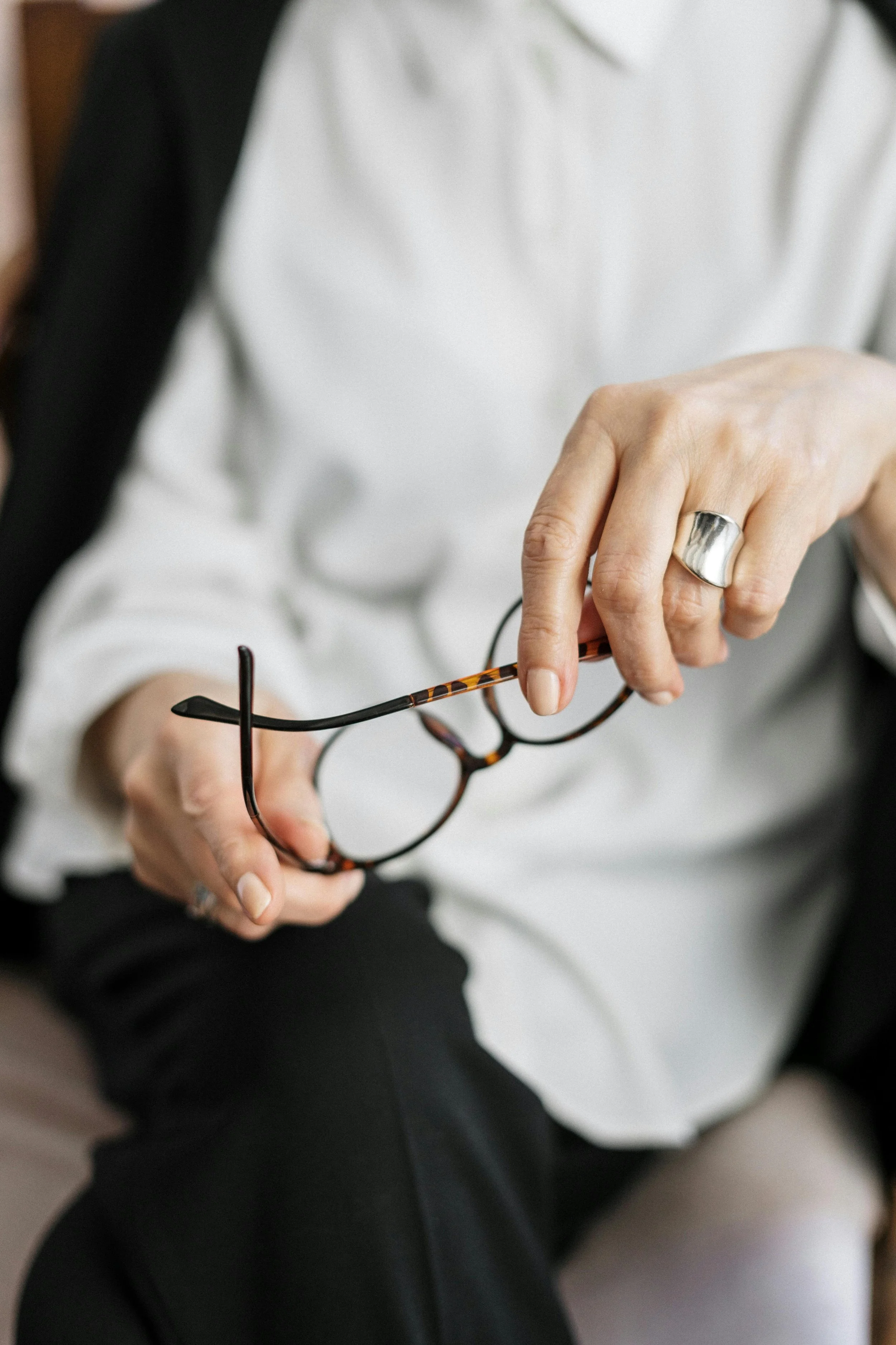 A person holding eyeglasses, representing thoughtful, personalized psychiatric care at A person holding eyeglasses, representing thoughtful, personalized psychiatric care at Embodied Psychiatry led by LaVeta Jarrett, PMHNP-BC