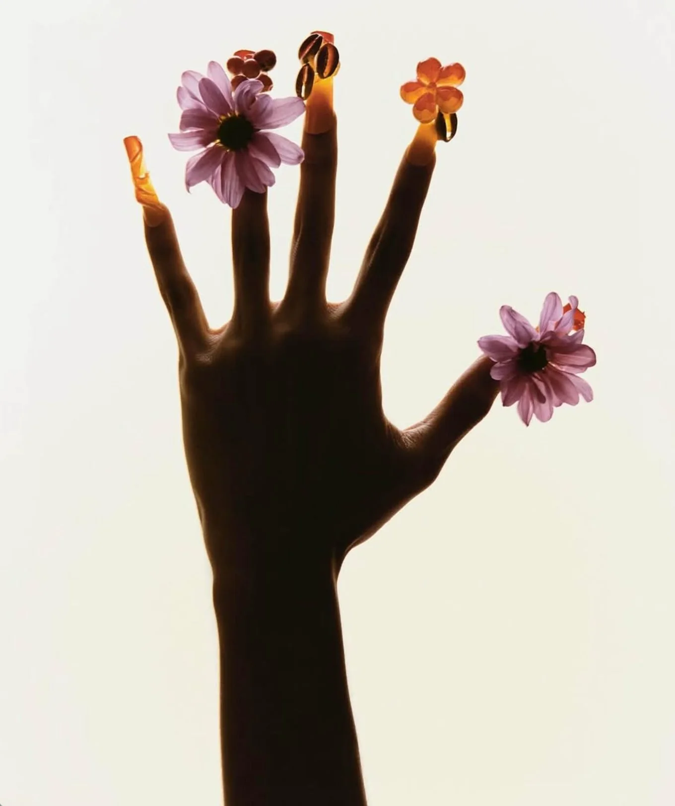 Mão com dedos decorados com flores e objetos decorativos