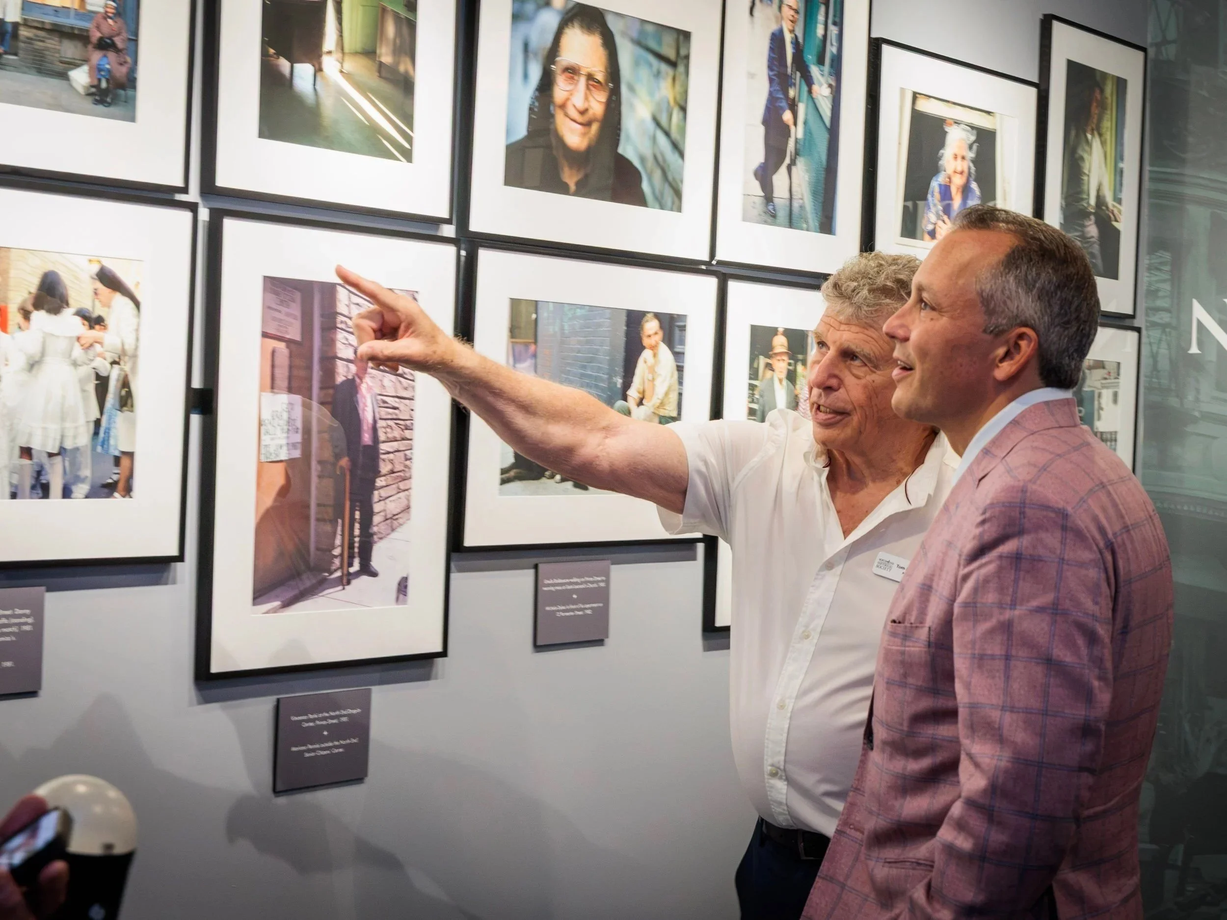 Two visitors at the wall of portraits and street photography of North End families.