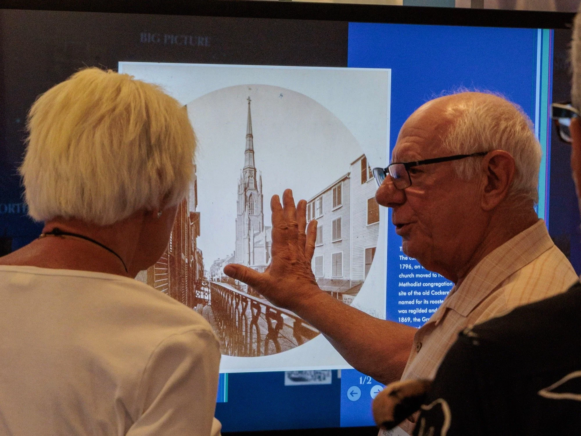 Two visitors exploring the history of a North End church on an interactive screen.