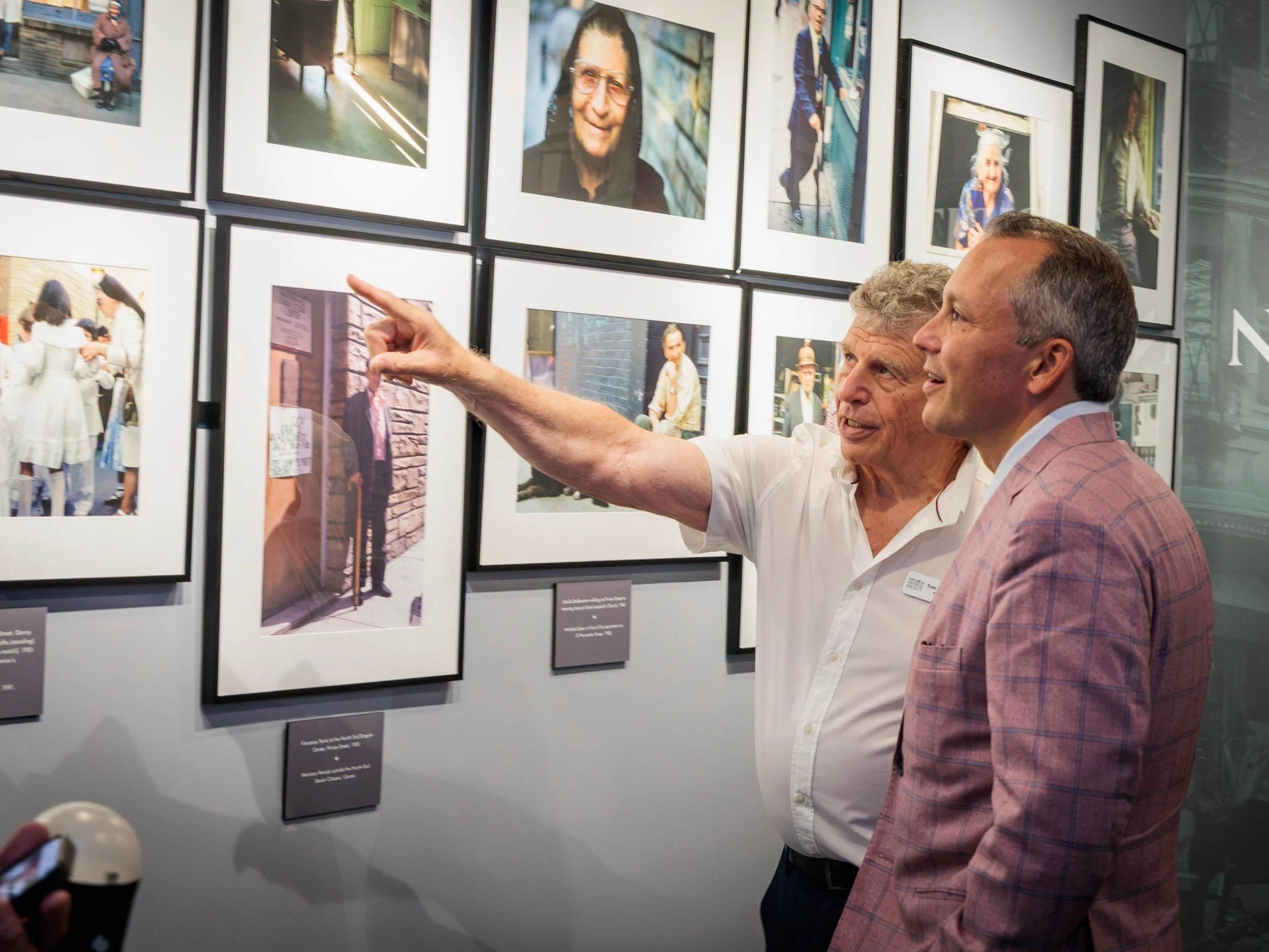 Two visitors at the wall of portraits and street photography of North End families.