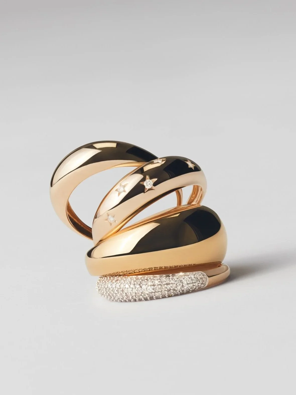 A collection of five gold rings with black accents, some decorated with stars and diamonds, displayed against a plain white background.