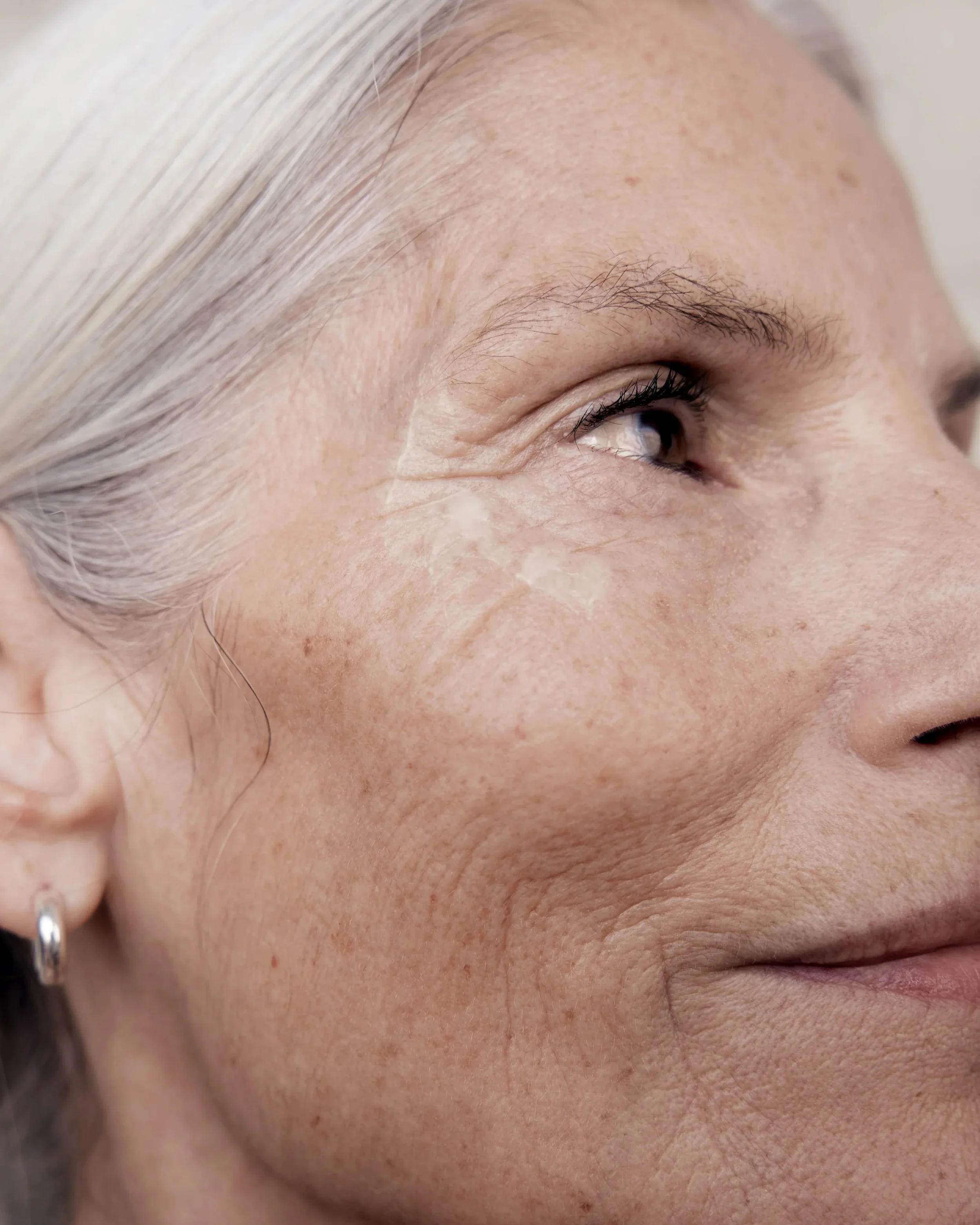 Close-up of a middle-aged woman's face highlighting skin texture, fine lines, and wrinkles around her eye and cheek.