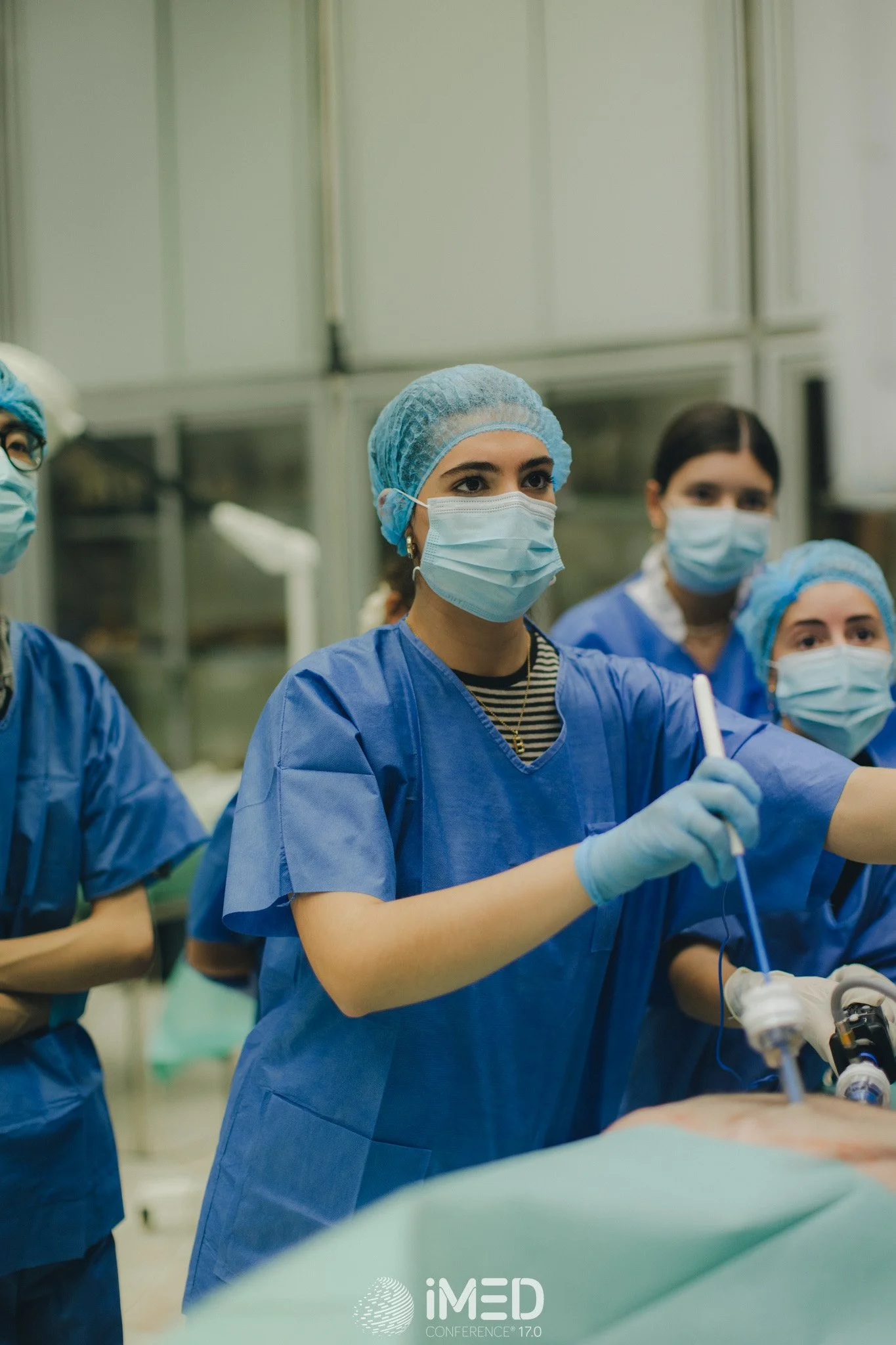 Group of medical professionals in surgical attire performing a procedure in an operating room.