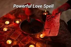 A love spell setup with candles, tarot cards, a black cauldron, and a red cloth, labeled 'Powerful Love Spell'.