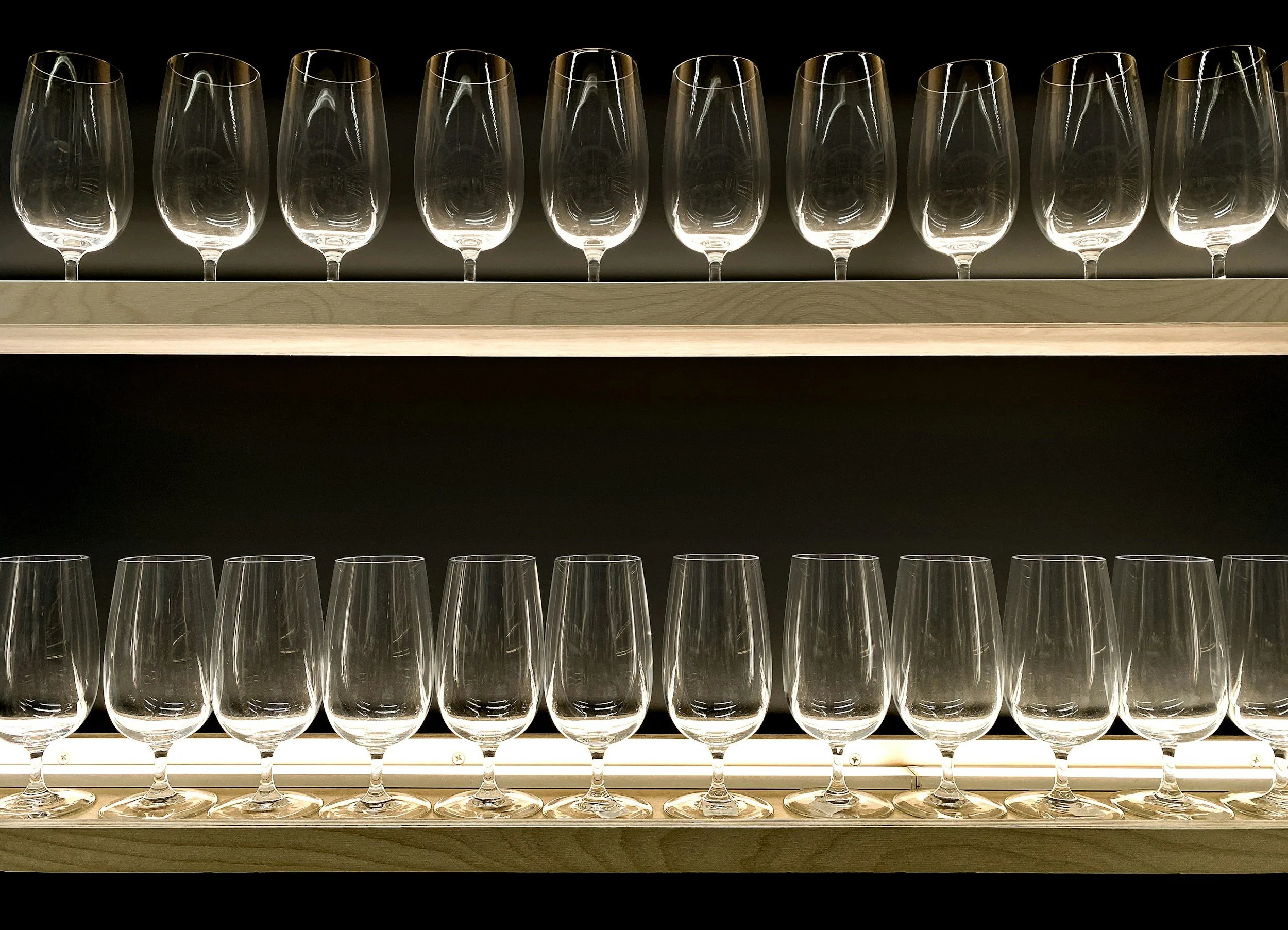 Shelves of wine glasses prepared for a Dolly's Occasions mobile bartending setup at an event.