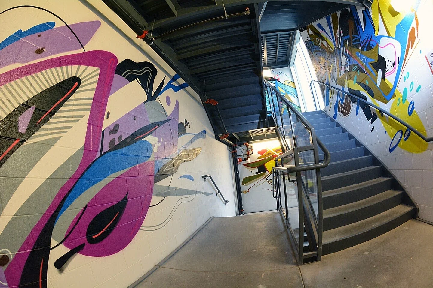 Colorful abstract mural art on the walls of a stairwell in a modern building. Collaborative mural with Rubén Aguirre Likes1.