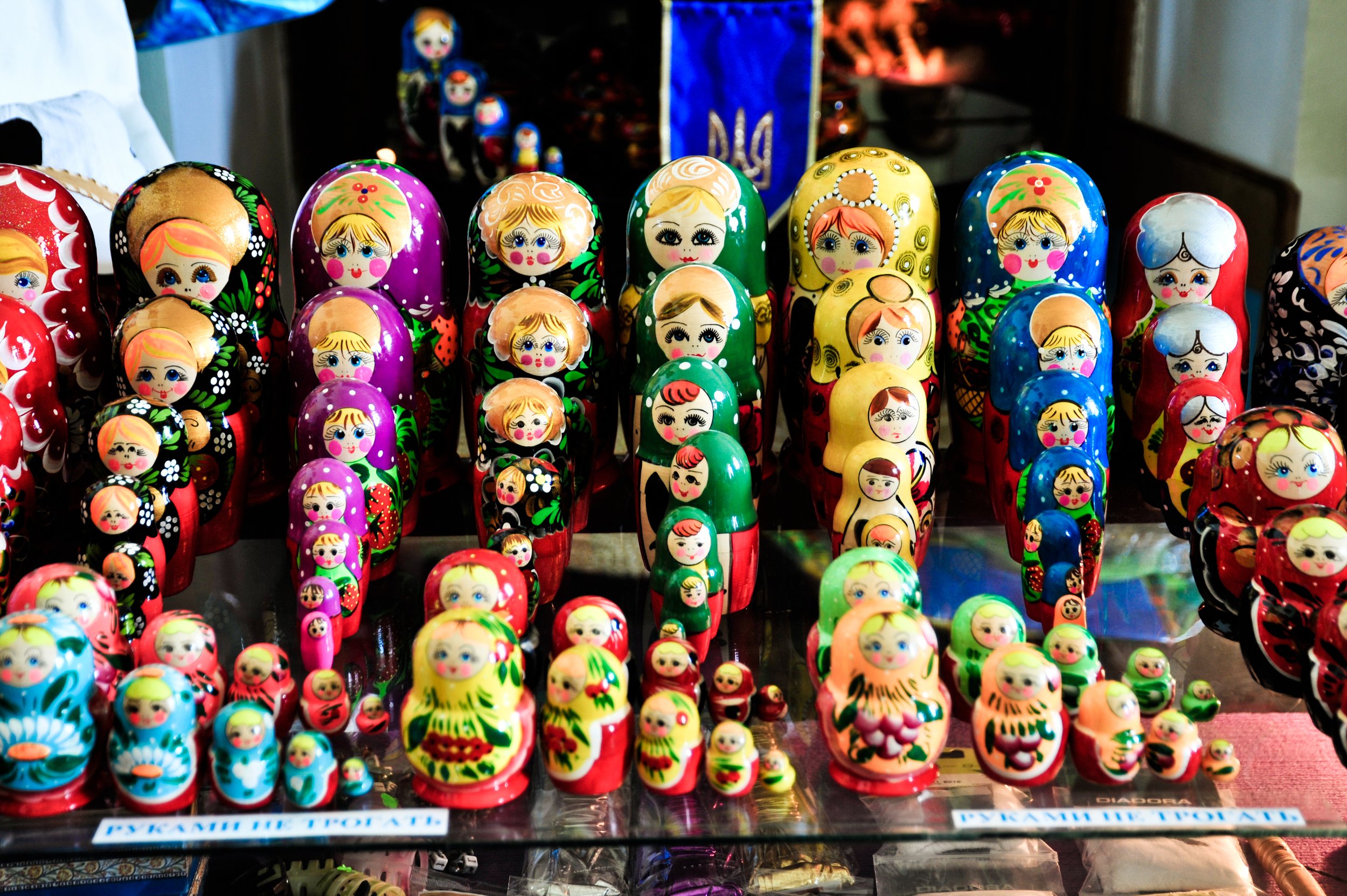 Collection of colorful Russian nesting dolls (Matryoshka) with various faces and designs displayed on a glass surface.