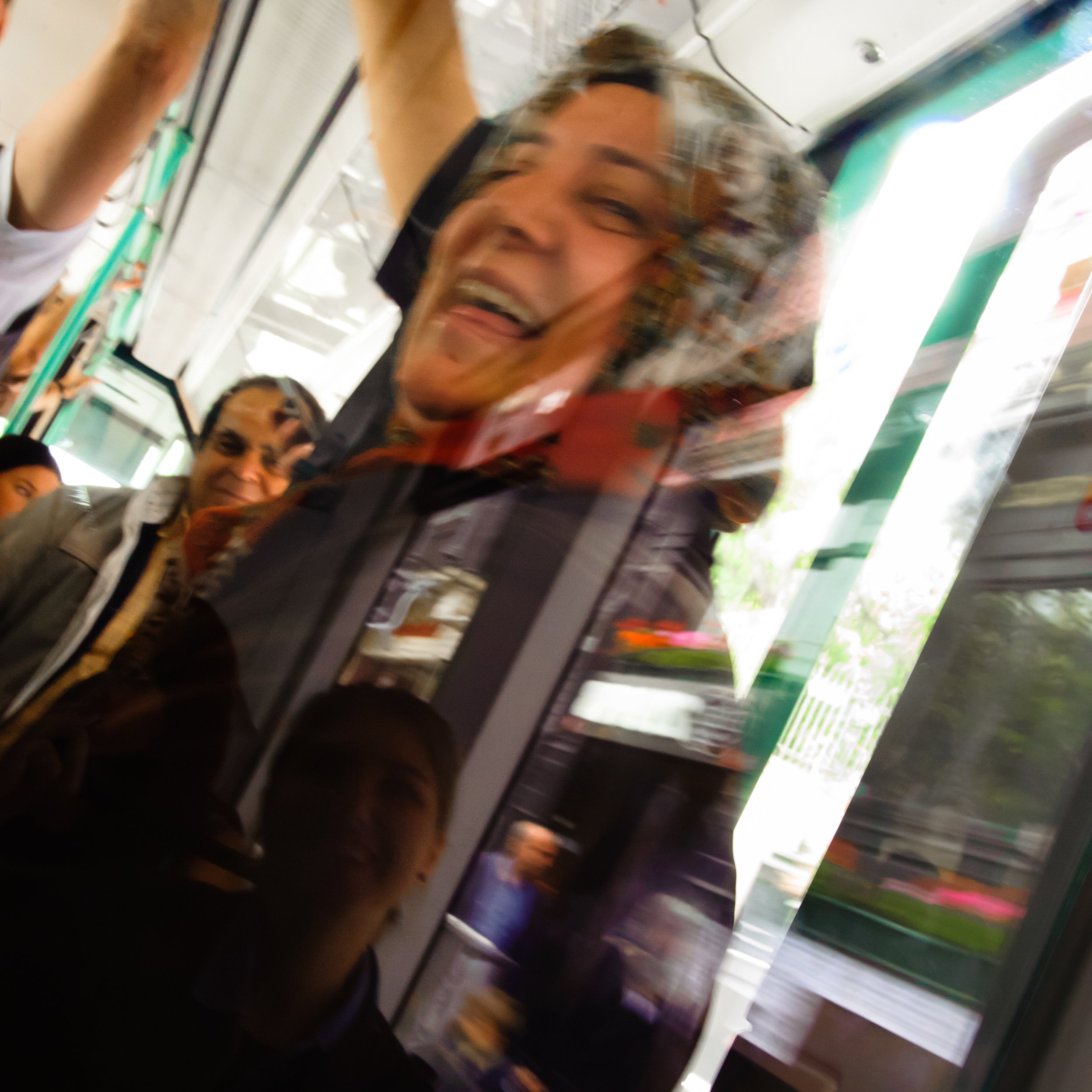 People smiling reflected on a mirror or glass surface, with a woman’s face prominently visible, capturing a joyful moment.