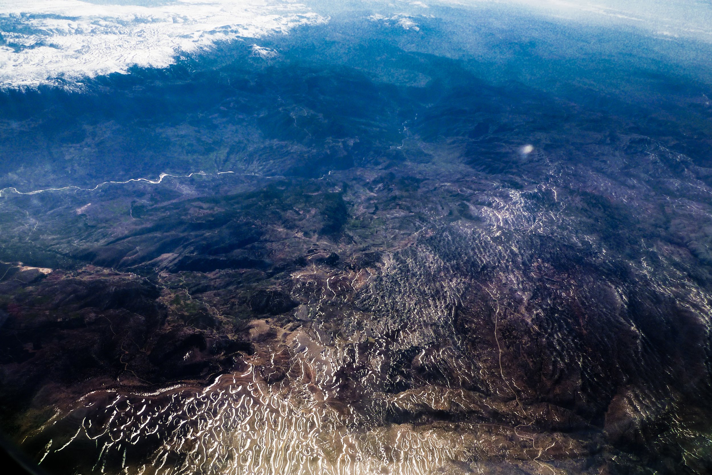 Aerial view of coastal mountains and ocean with waves crashing on the shoreline.