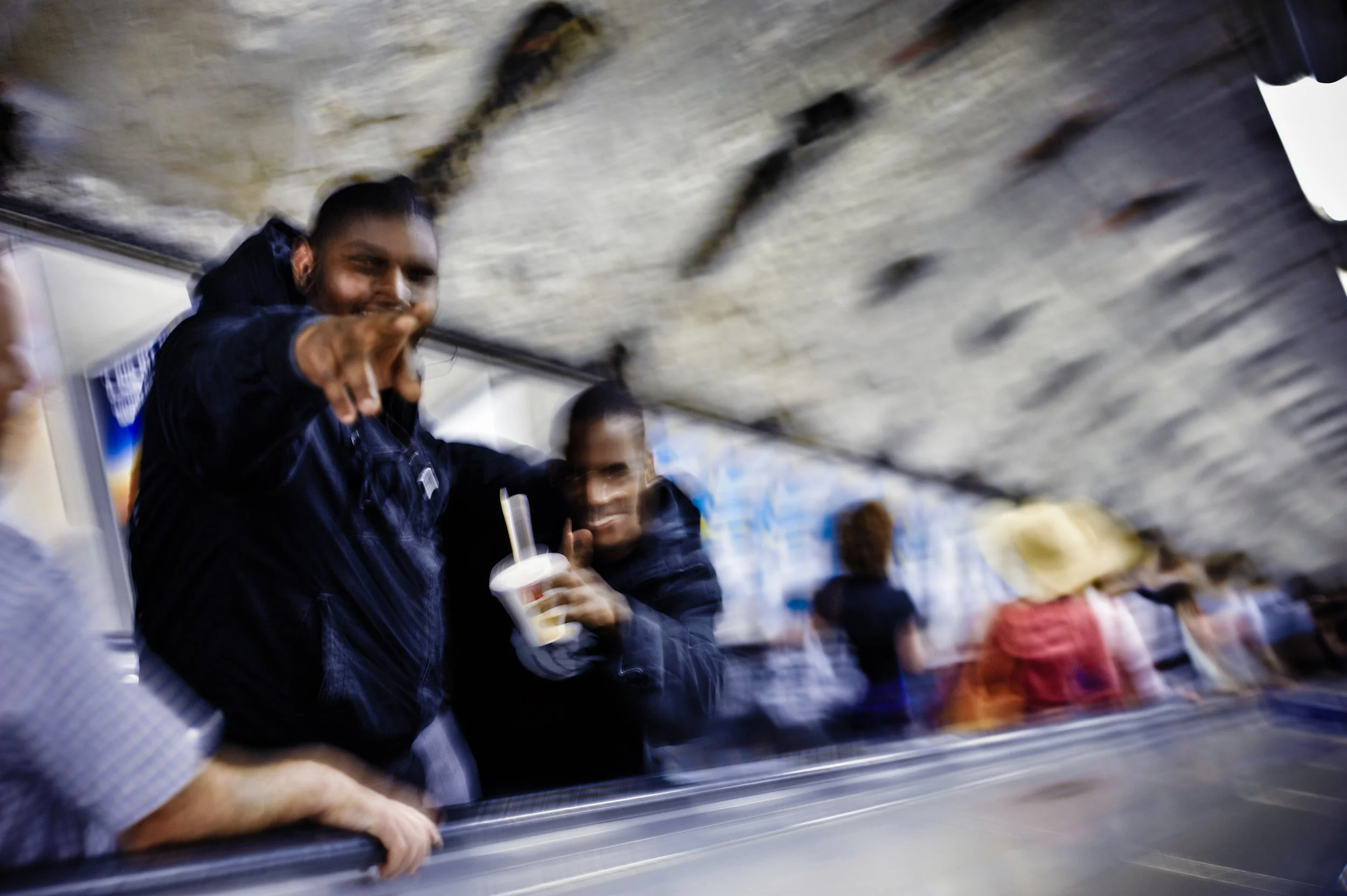 People in a crowded underground station or subway, with some holding drinks, and others moving through the space.
