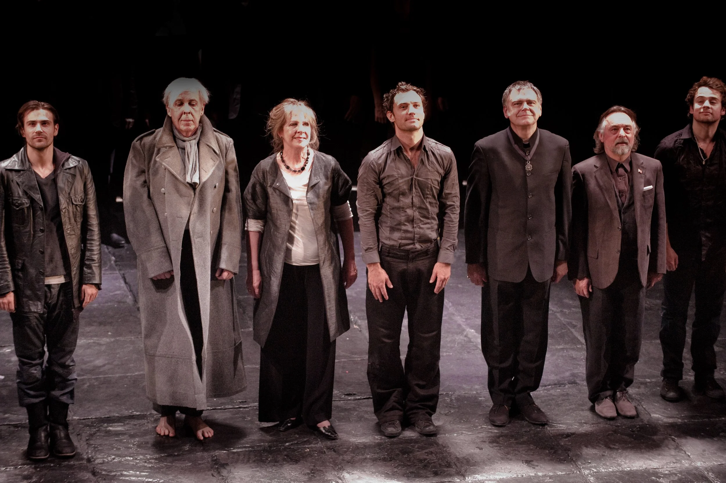 Group of actors standing in a line on a stage, taking a bow after a performance.