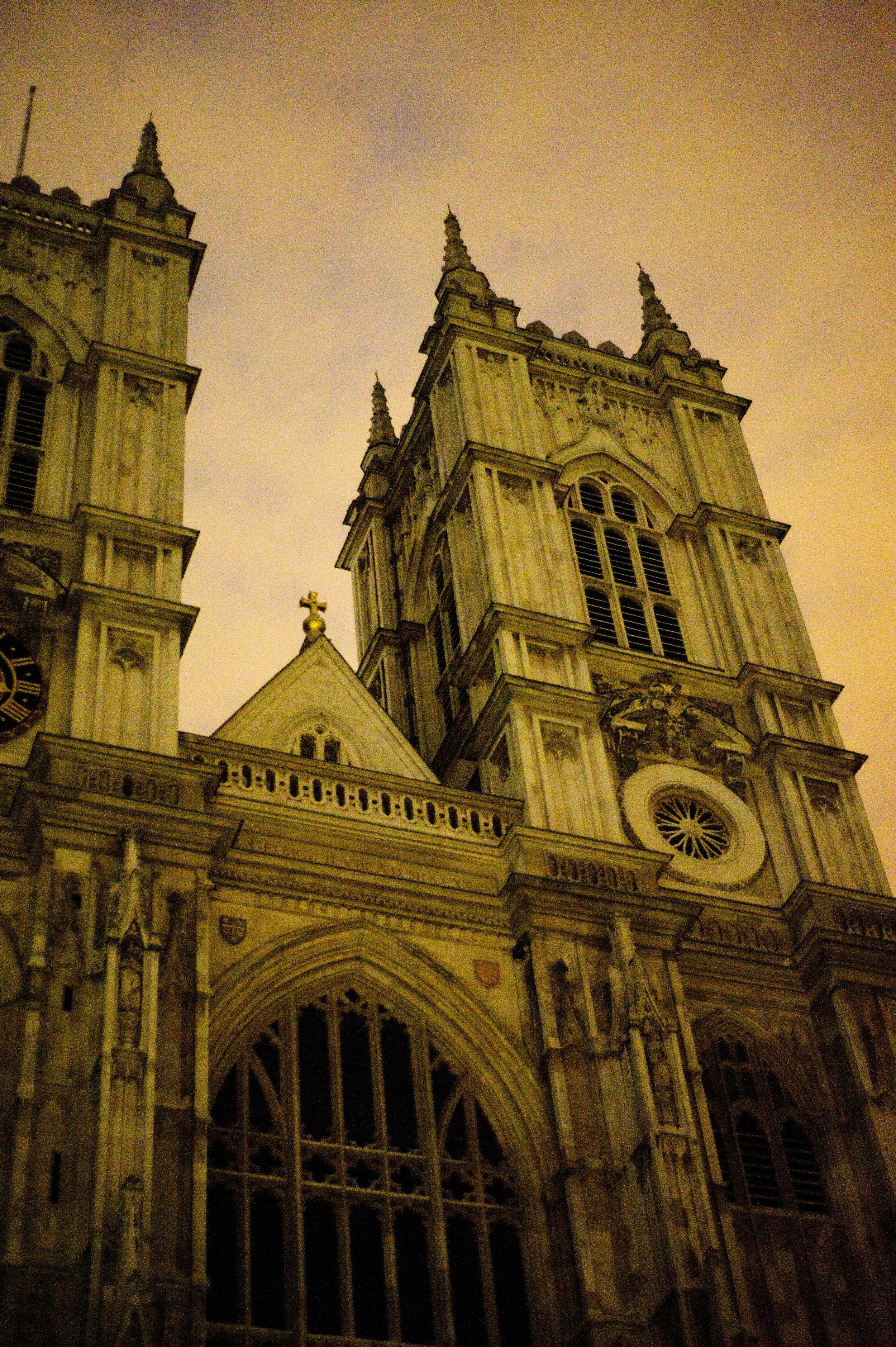 Night view of a large Gothic-style church with tall spires, intricate stonework, large arched window, and illuminated facade.