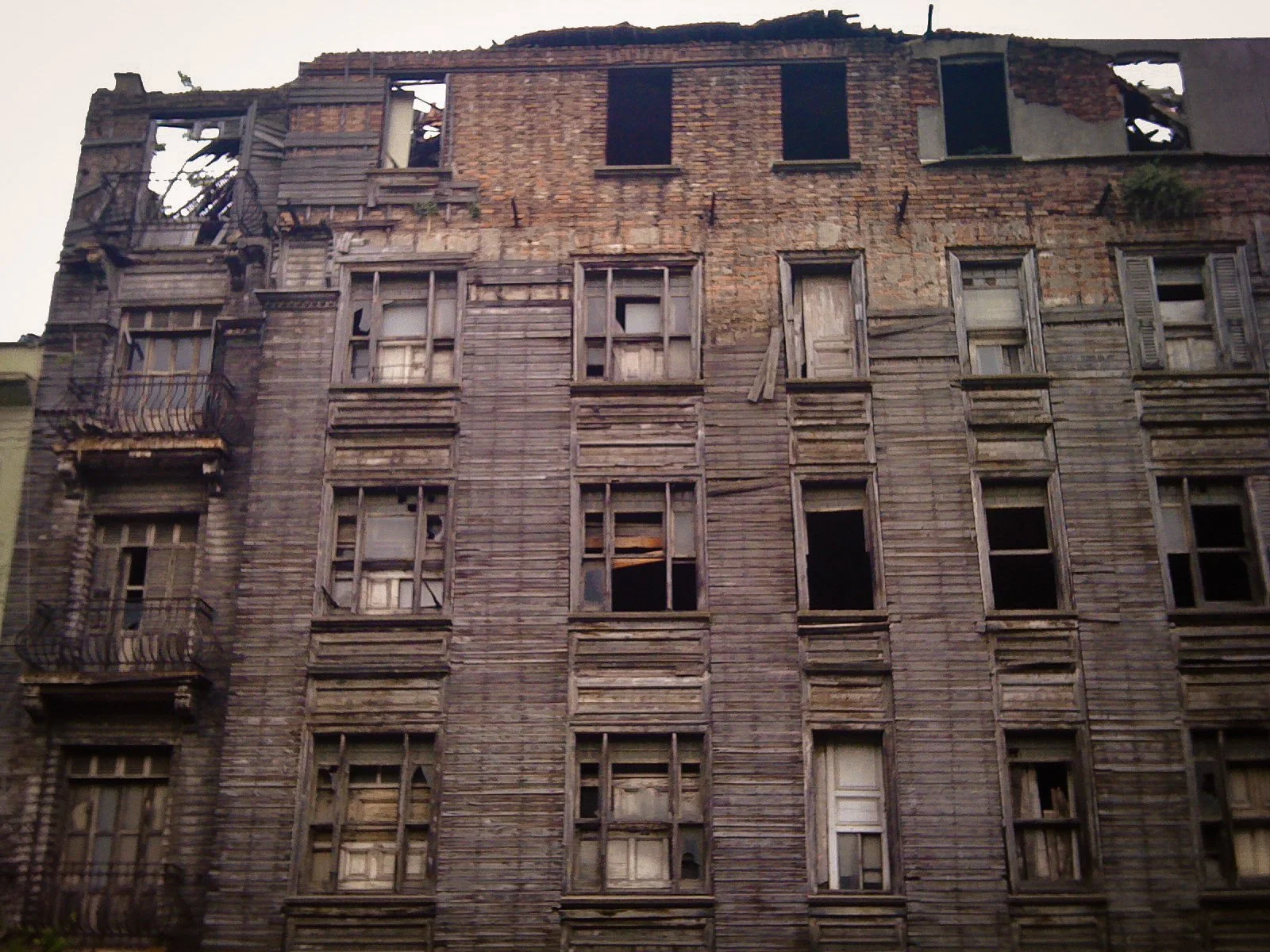 An old, dilapidated multi-story building with deteriorating wooden and brick exterior and broken or missing windows.
