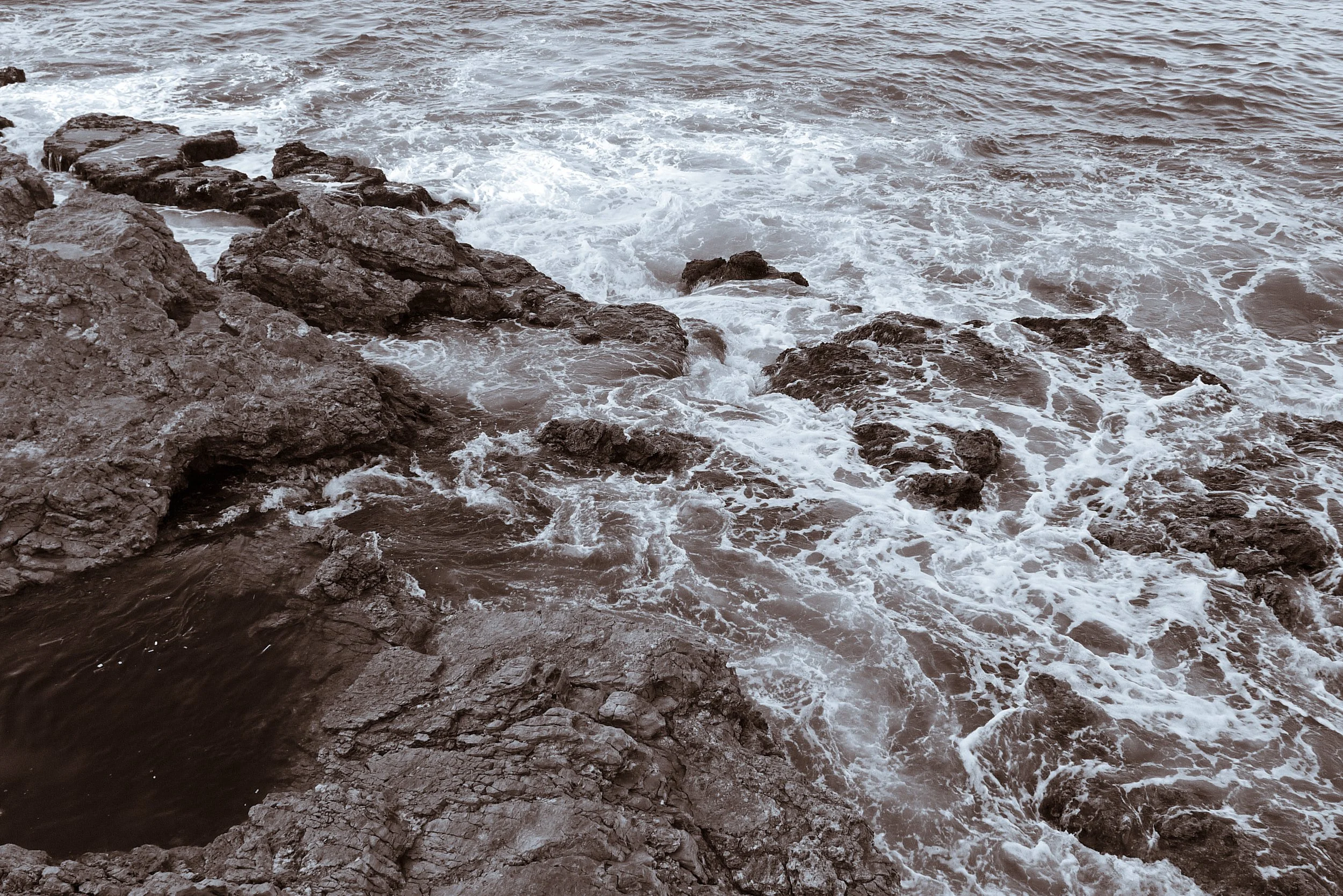 View of a rocky shoreline with waves crashing against rocks in the ocean