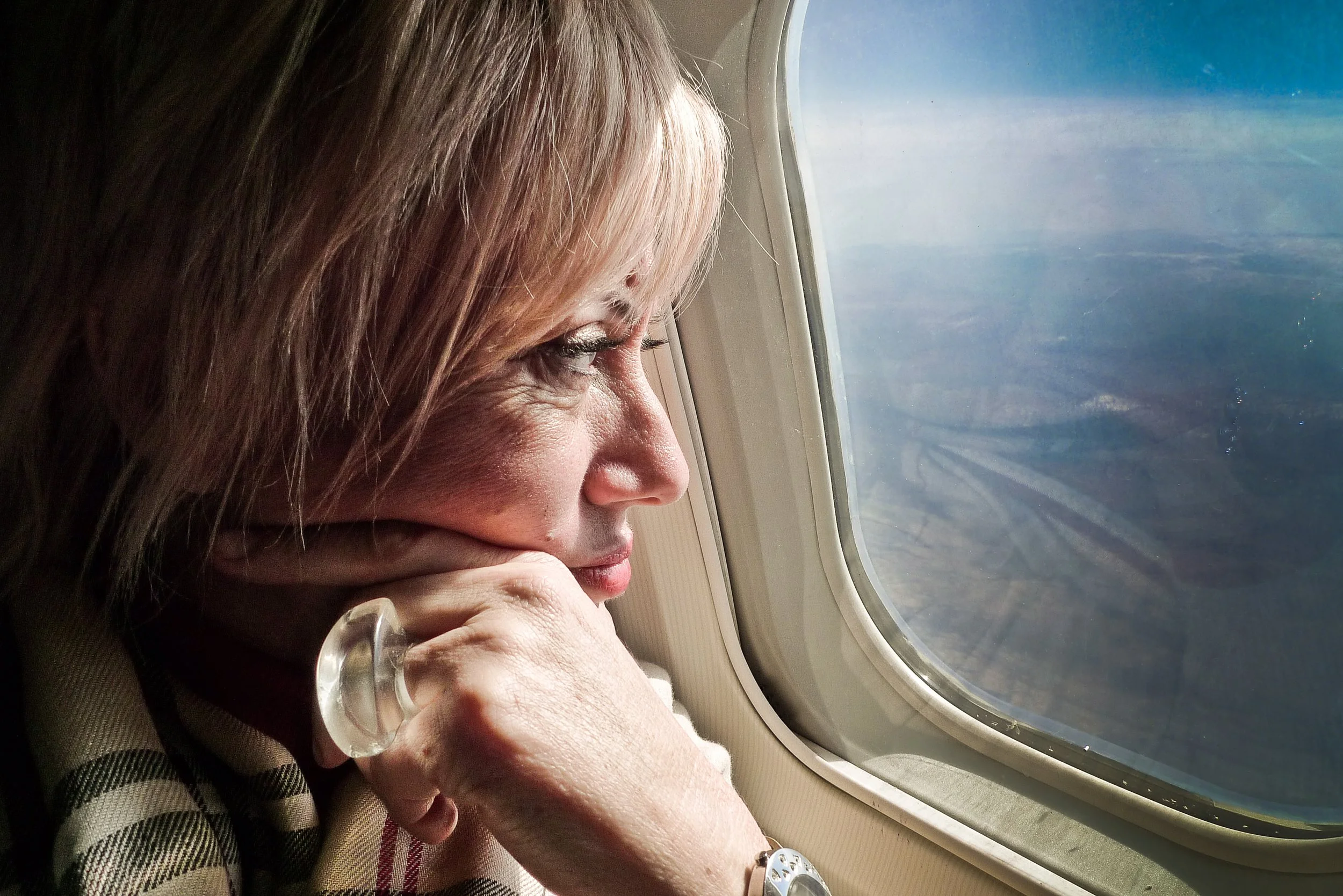 Woman looking out airplane window with thoughtful expression