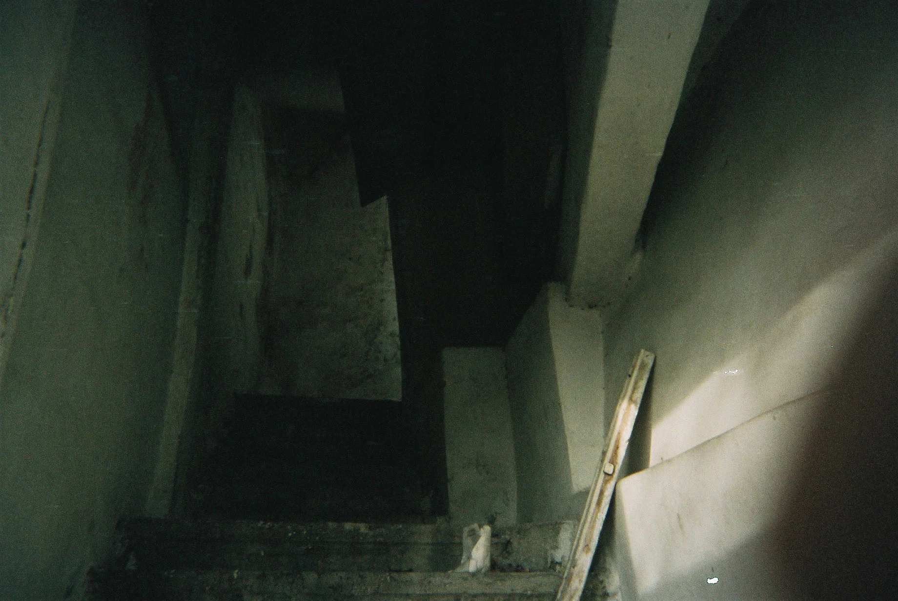 A dark, unfinished staircase inside a building under construction, with construction materials and tools visible.