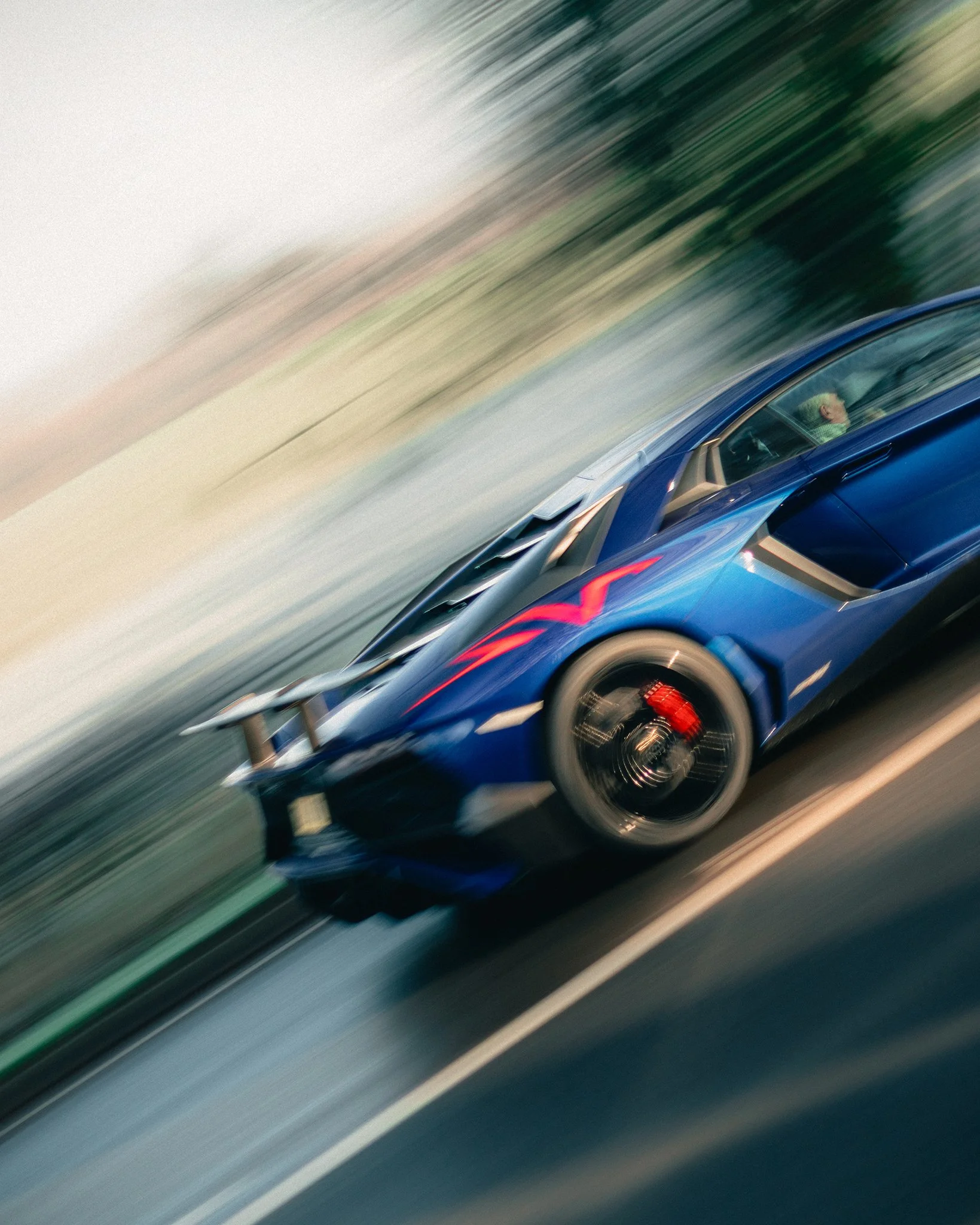A blue Lamborghini Aventador SV accelerating in the cold winter morning light