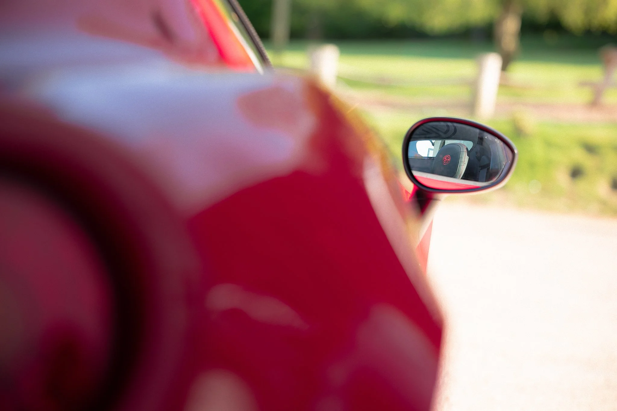 A detail shot of the Alfa Romeo insignia that is embroidered into the driver's seat of an Alfa Romeo 4C, framed using the wing mirror of the car