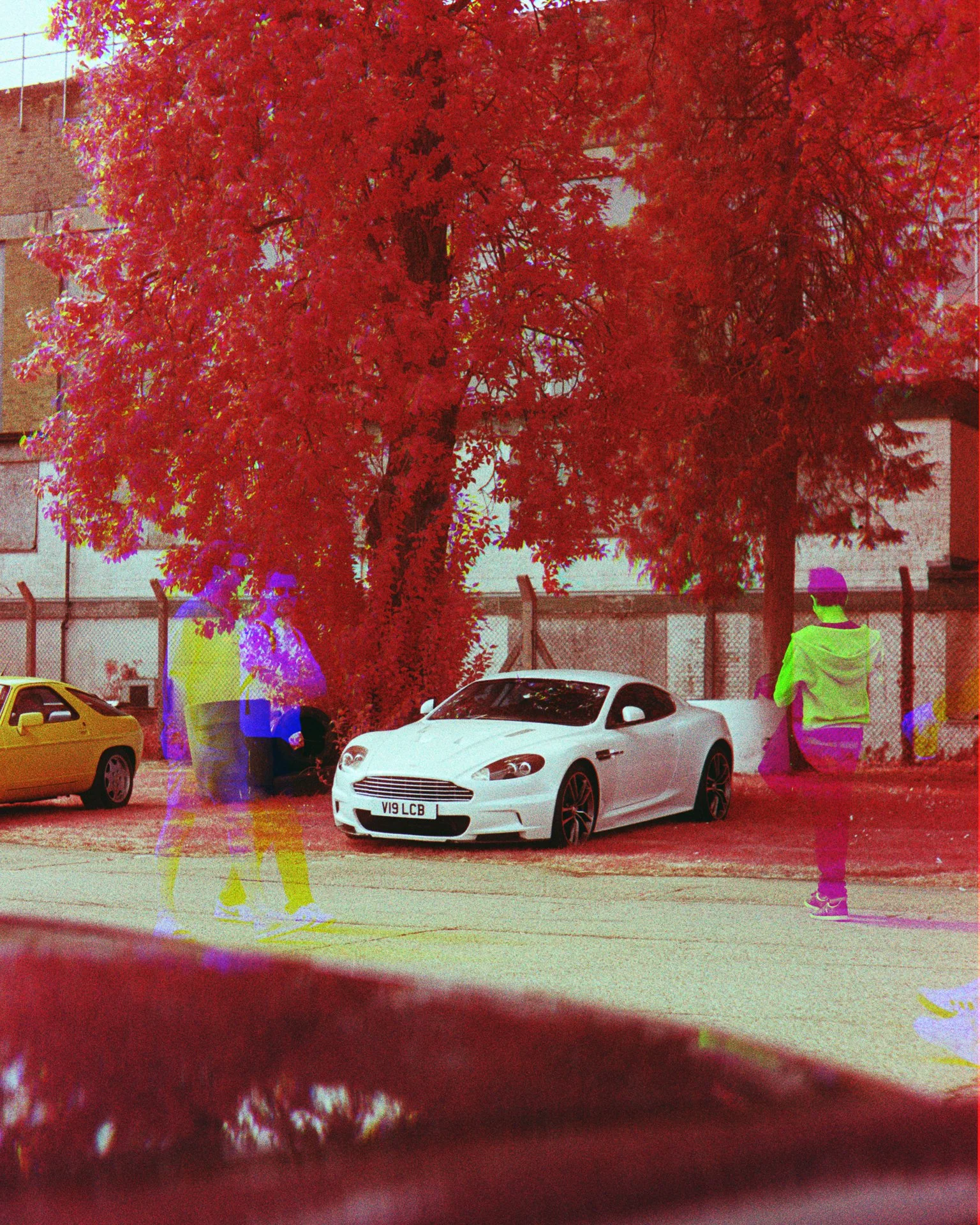 A triple-exposure false-colour infrared film photo of an Aston Martin DBS