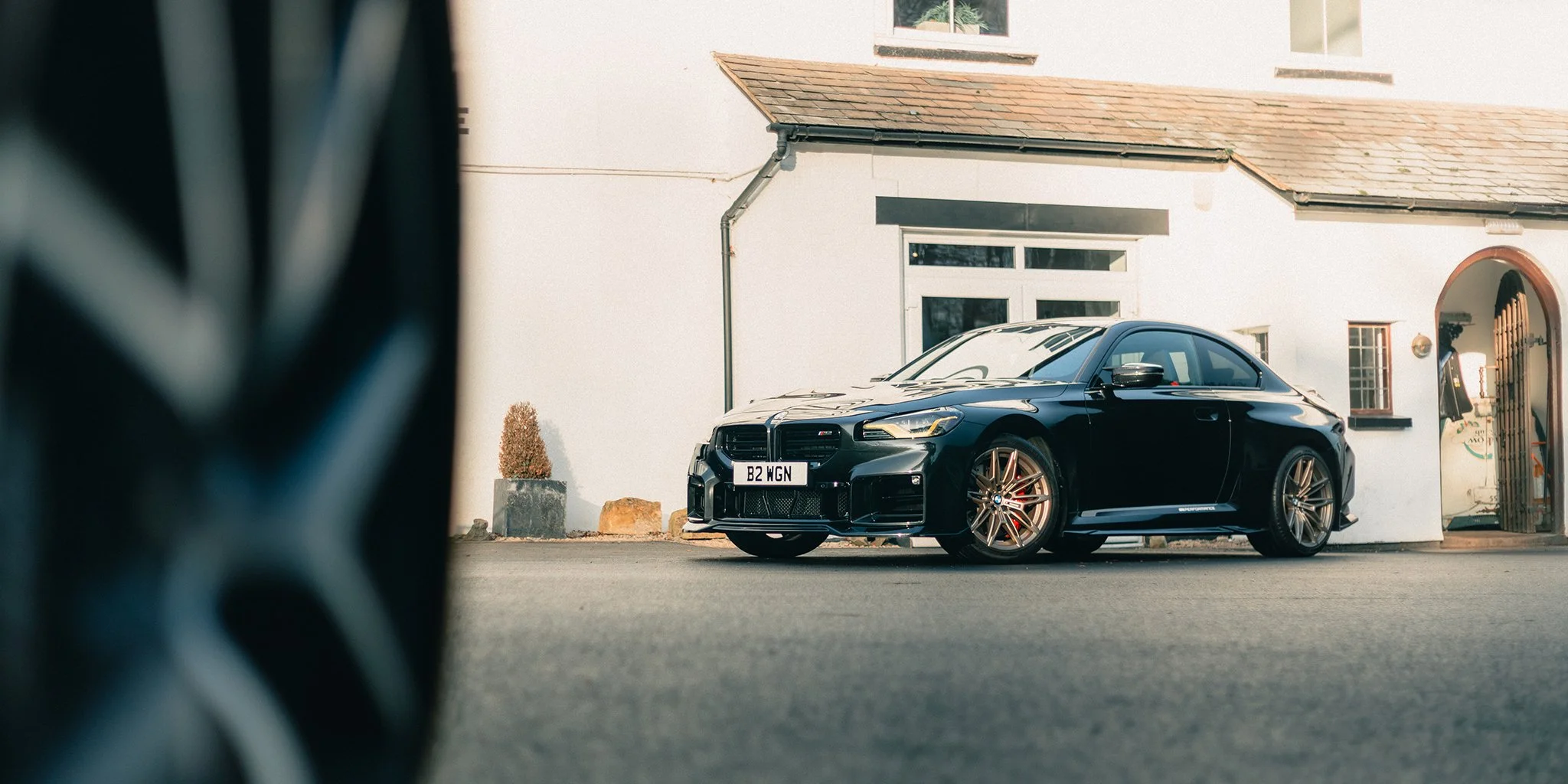 A black BMW M2 posed in front of a white building
