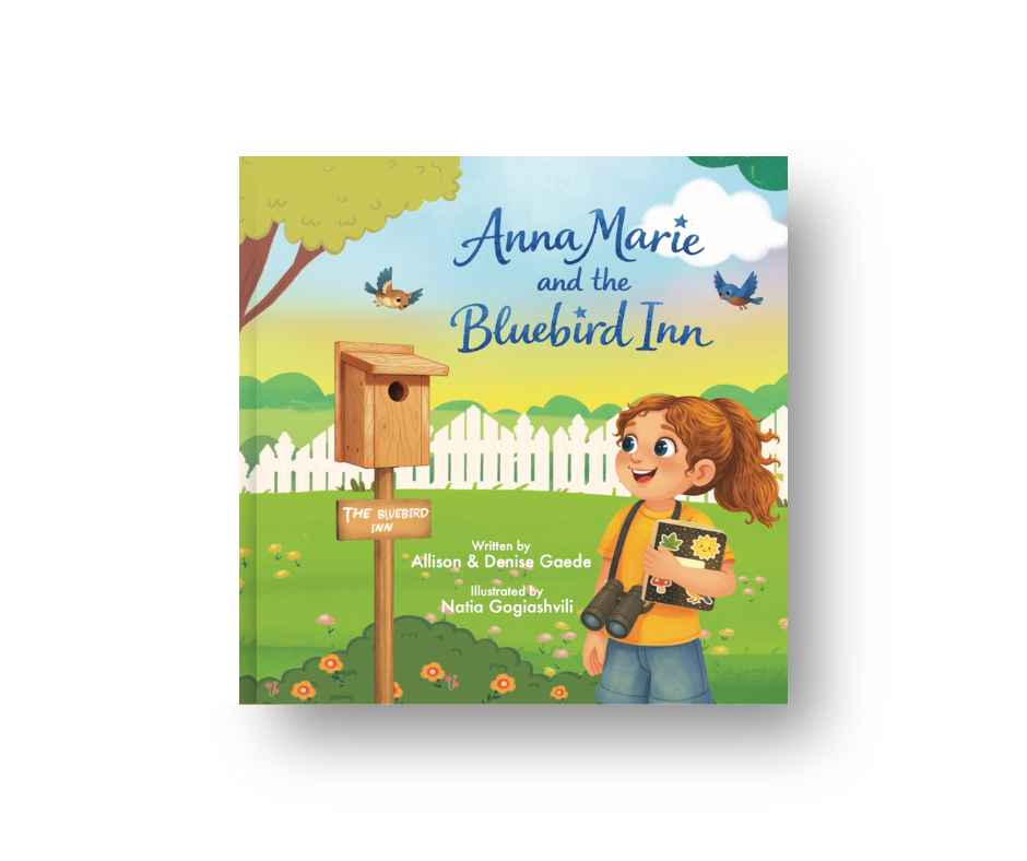 Children's book cover titled 'Anna Marie and the Bluebird Inn,' featuring a girl with red hair holding a book and binoculars, standing outdoors near a birdhouse with a white picket fence and trees, rainbows, and birds in the background.